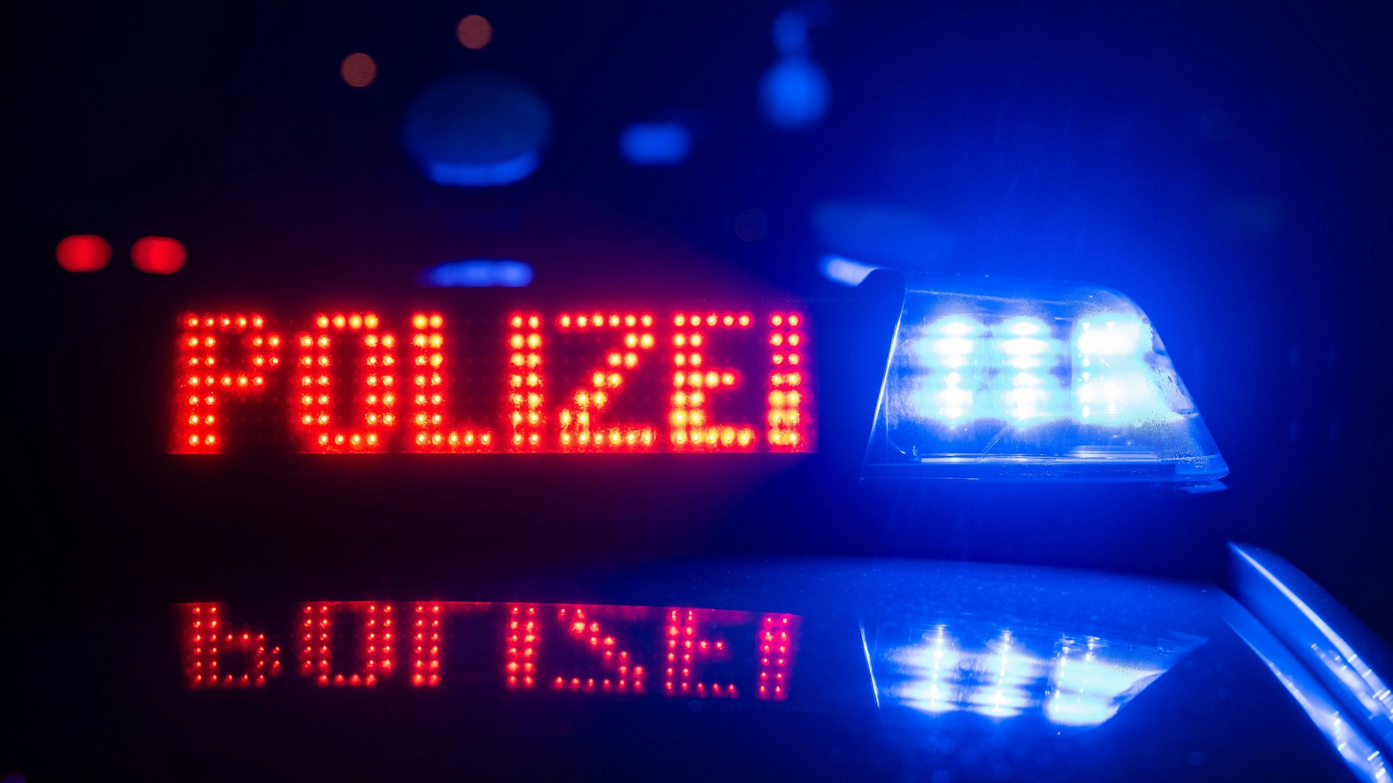 Zwei Polizisten stehen im Rahmen eines Fototermins vor einem Polizeifahrzeug (gestellte Szene).