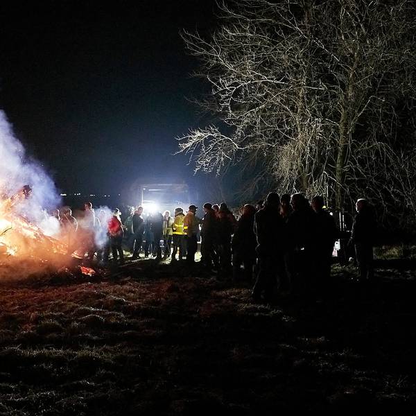 Zahlreiche Menschen stehen an einem größeren Mahnfeuer.