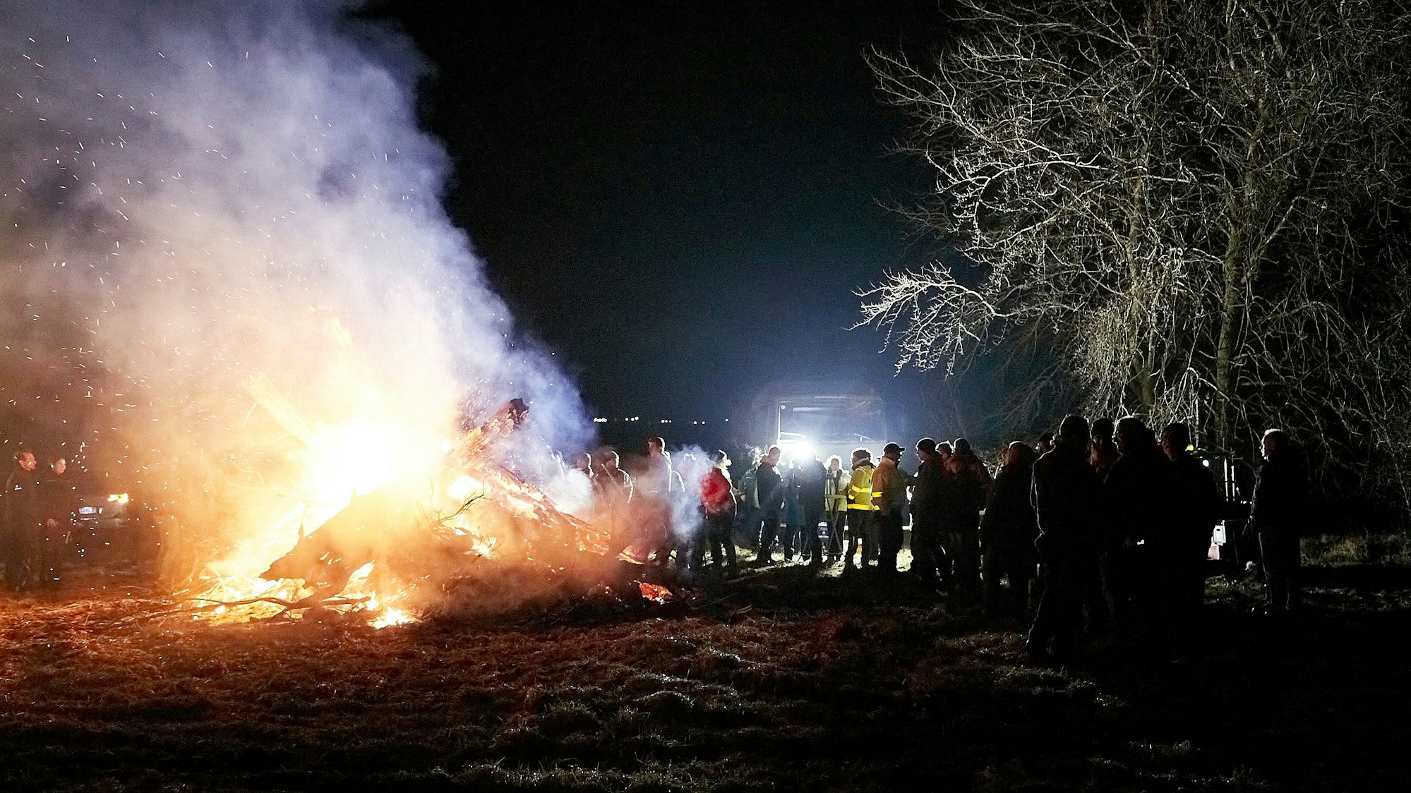 Zahlreiche Menschen stehen an einem größeren Mahnfeuer.