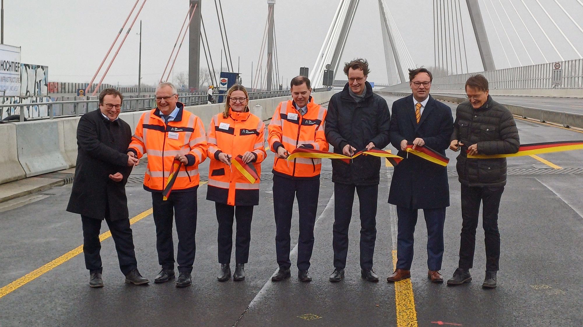Verkehrsminister Oliver Krischer, Thomas Ganz, Nicole Ritterbusch, Michael Günther, Hendrik Wüst, Oliver Luksic und Karl Lauterbach beim Durchschneiden des schwarz-rot-goldenen Bandes.