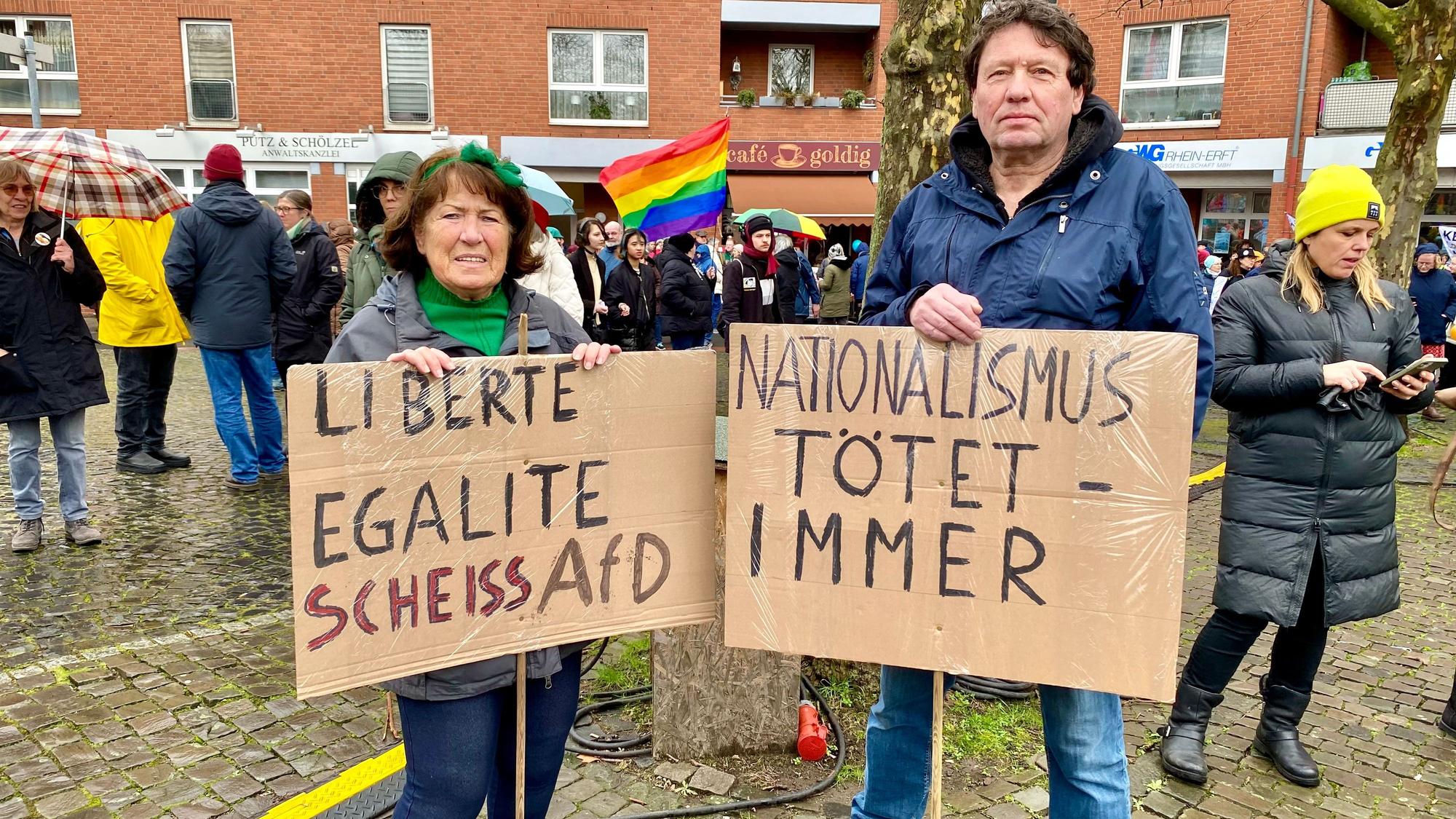 Auf dem Bild sind zwei Demonstraten mit Schildern zu sehen.
