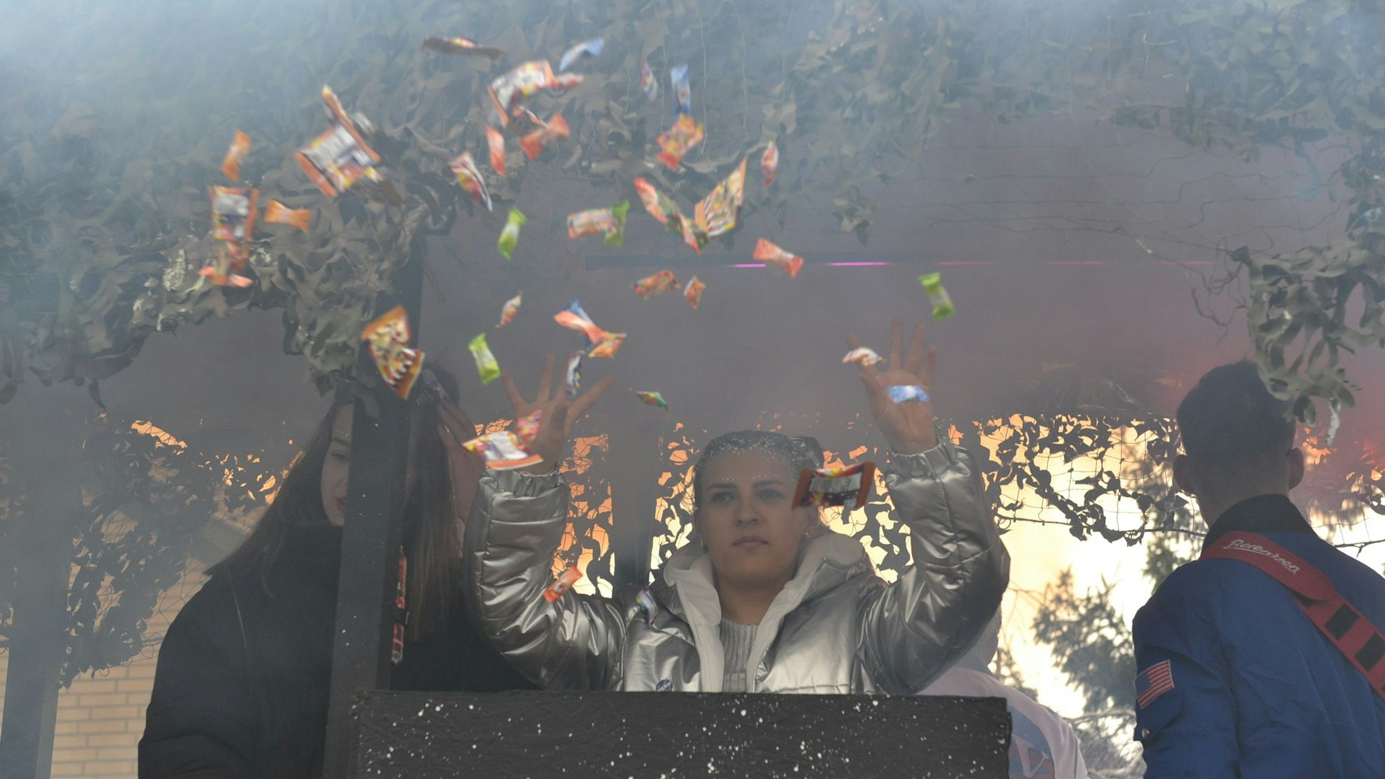 Ein junges Mädchen wirft von einem Karnevalswagen Kamelle und Süßigkeiten.