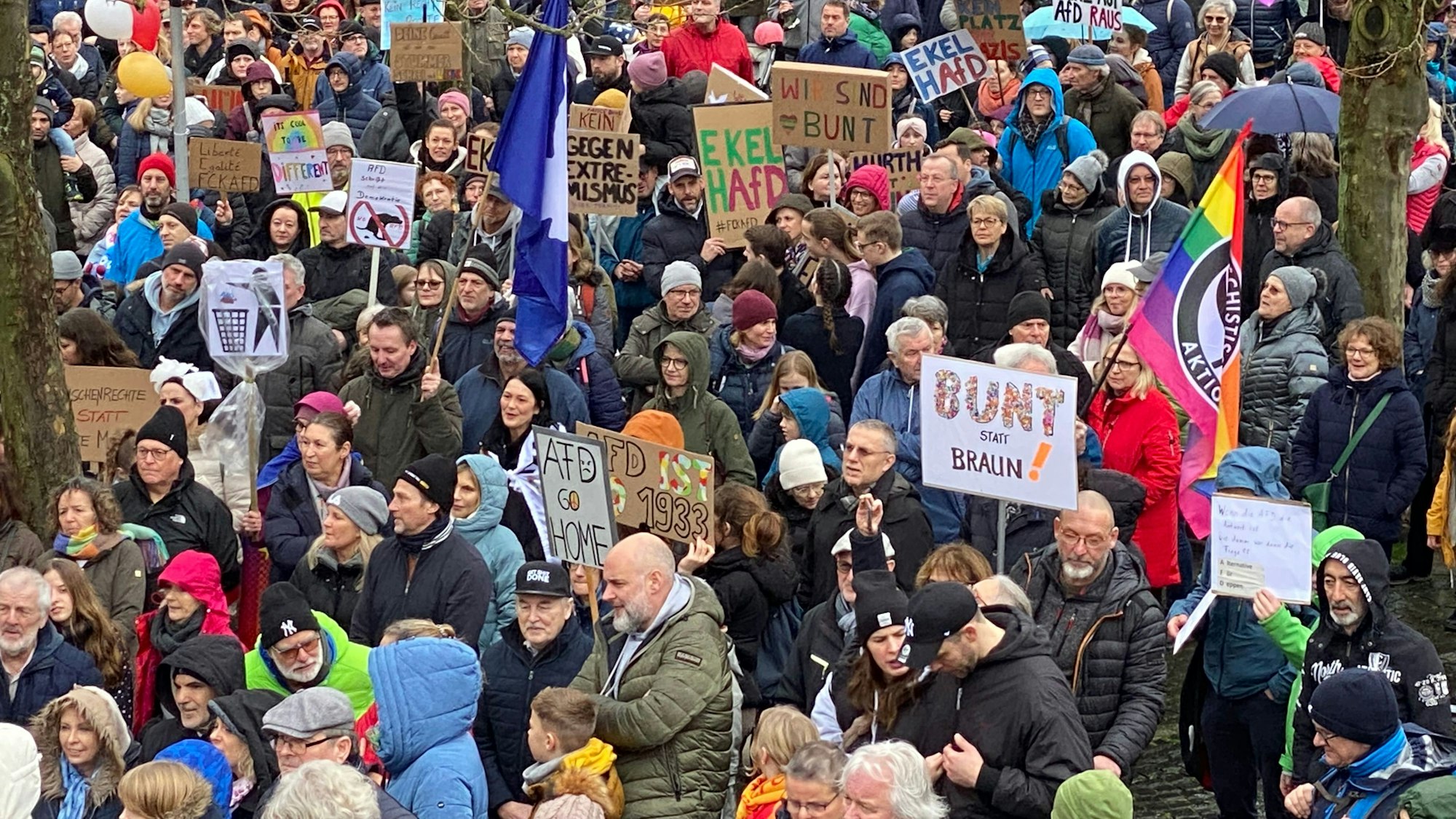 Das Foto zeigt Menschen mit Fahnen und Transparenten bei der Kundgebung gegen Rechtsextremismus in Hürth Anfang Februar 2024.
