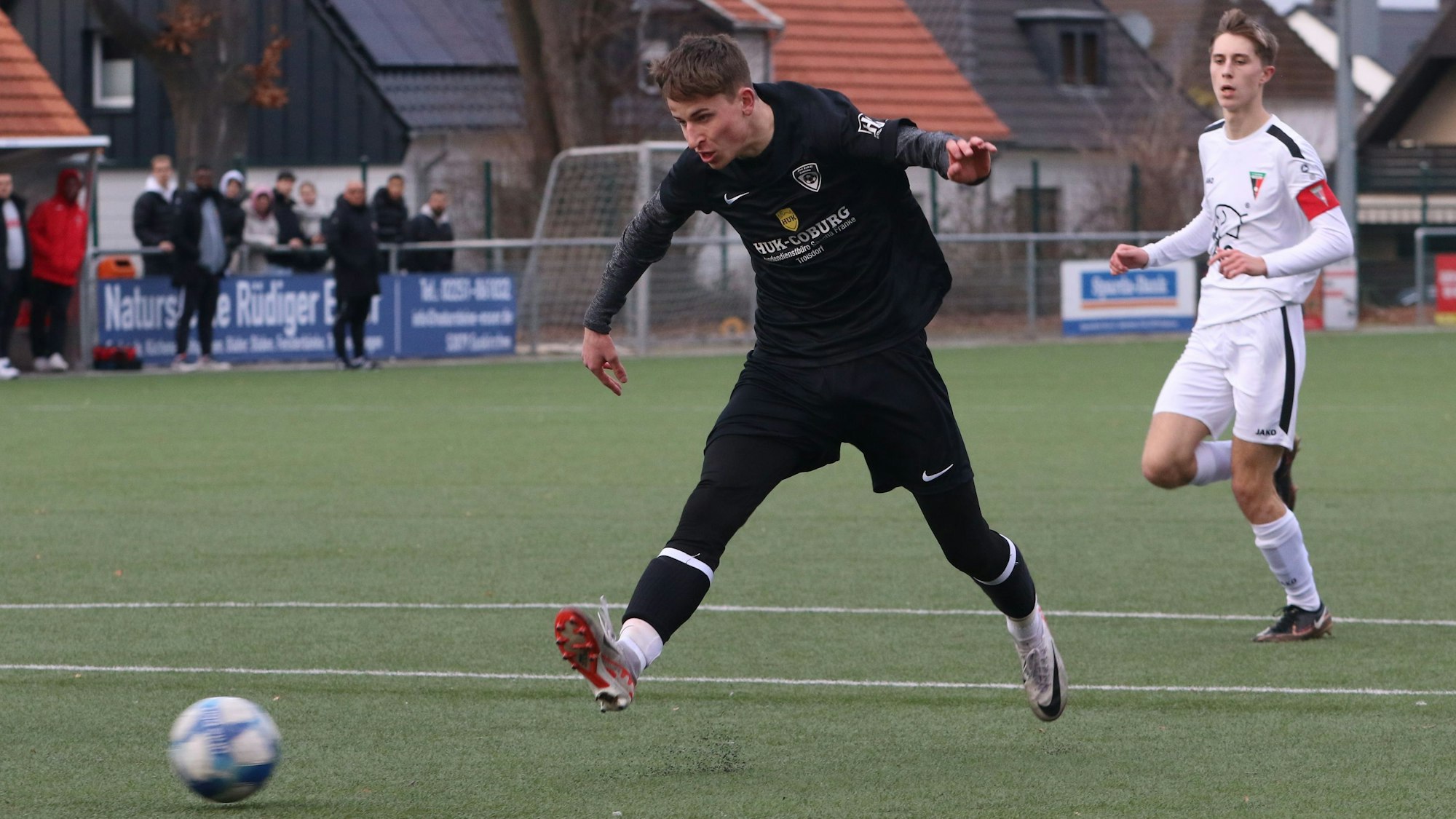 Julius Prasmo-Klaßen schießt aufs Tor. Der Ball ist leicht unscharf. Der gegnerische Kapitän schaut aus der Entfernung zu.