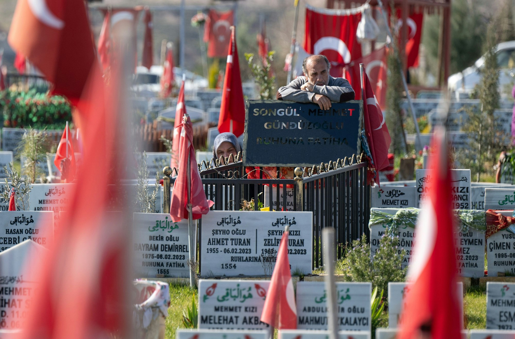 Adiyaman: Am Grab ihrer beim Erdbeben getöteten Familienmitglieder stehen ein Mann und eine Frau auf einem Gräberfeld am Rande von Adiyaman in der Türkei. Kurz vor dem ersten Jahrestag der Erdbebenkatastrophe kommen hunderte Angehörige zu den Gräbern ihrer Angehörigen, die bei dem Beben am 6. Februar 2023 umgekommen waren.