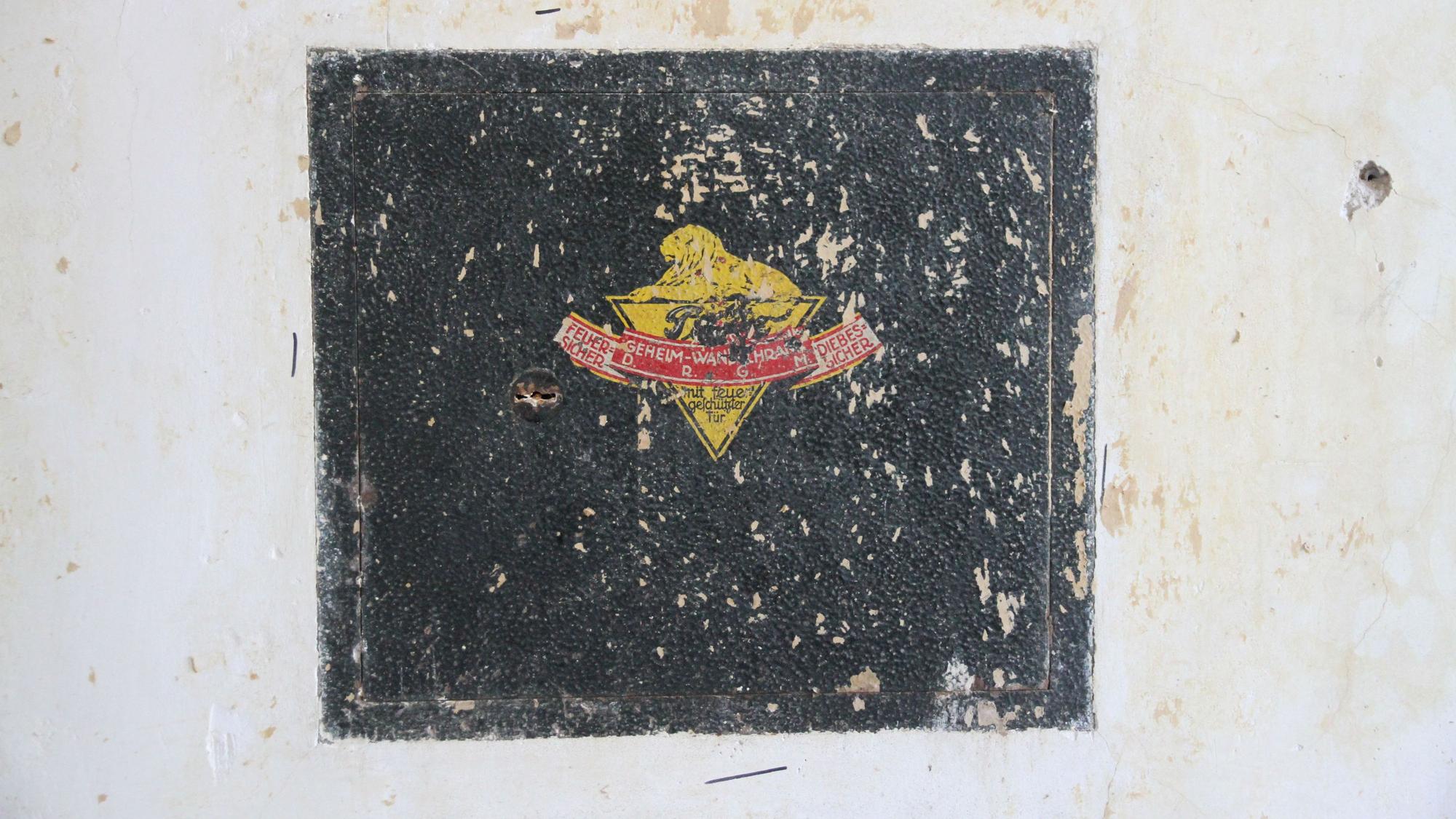 Ein alter Wandtresor mit gelb-rotem Firmenemblem