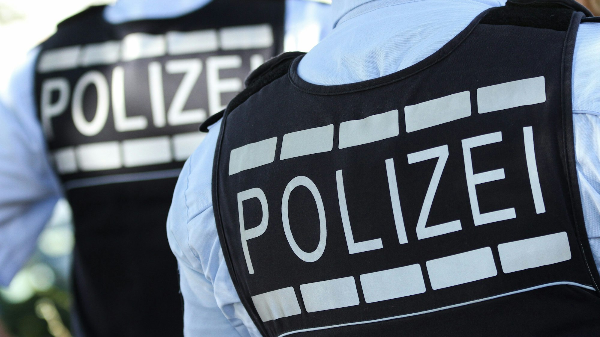 Nahaufnahme auf zwei Einsatzkräfte der Polizei in Westen mit „Polizei“ Aufschrift (Symbolbild)