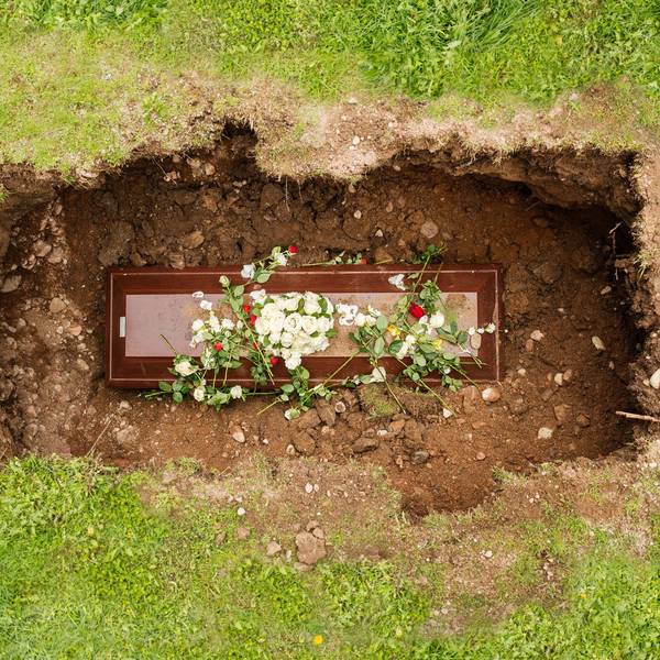 Ein Sarg mit Blumen in einem geöffneten Grab