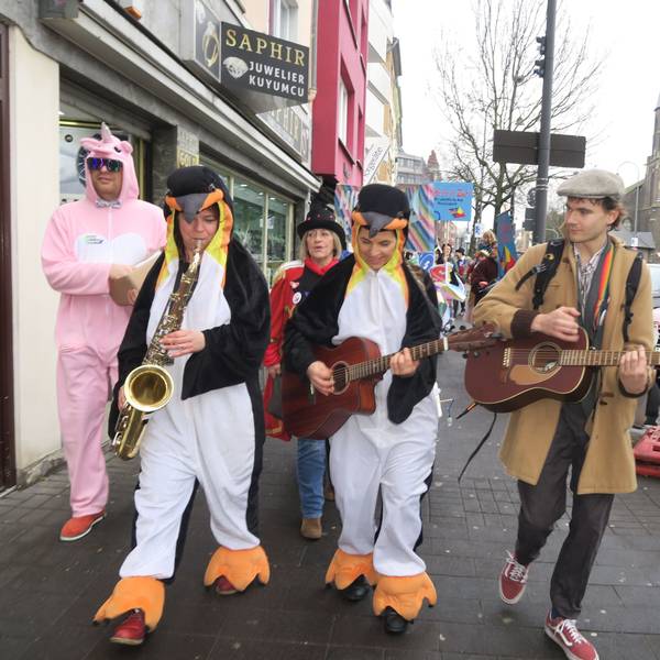 Mit Gitarren und Saxofon zieht eine Gruppe eine Straße entlang.
