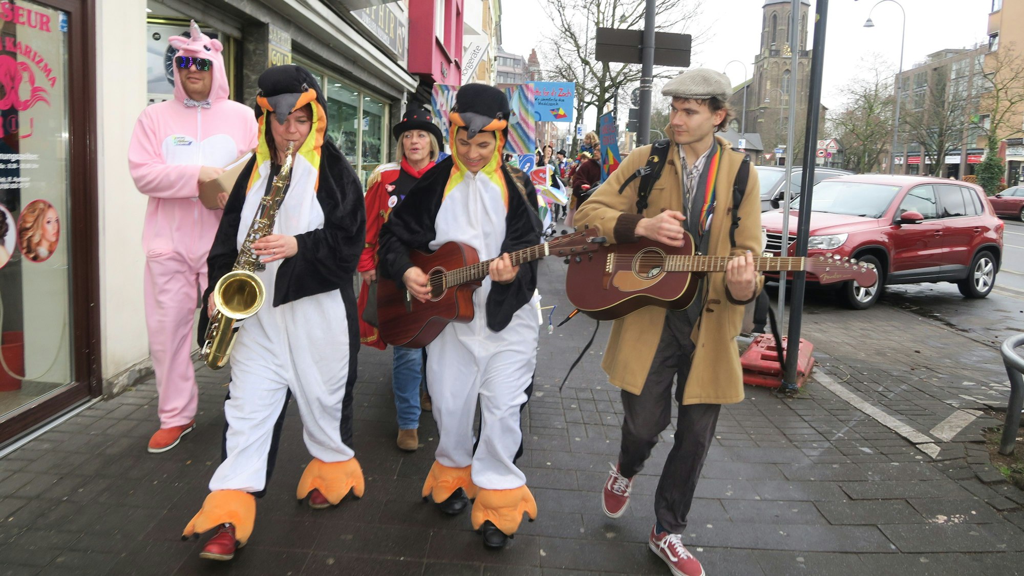 Mit Gitarren und Saxofon zieht eine Gruppe eine Straße entlang.