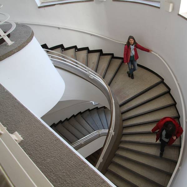 Zwei Frauen lauen eine gewundene Treppe herunter.