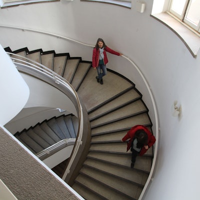 Zwei Frauen lauen eine gewundene Treppe herunter.