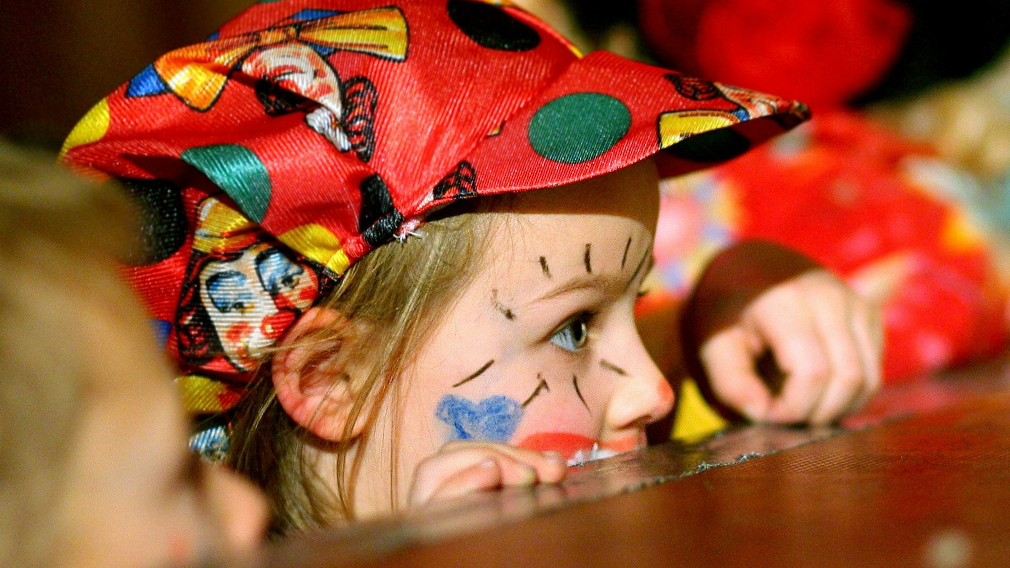 Zu sehen ist ein Kind im Clown-Kostüm auf einer Karnevalssitzung.