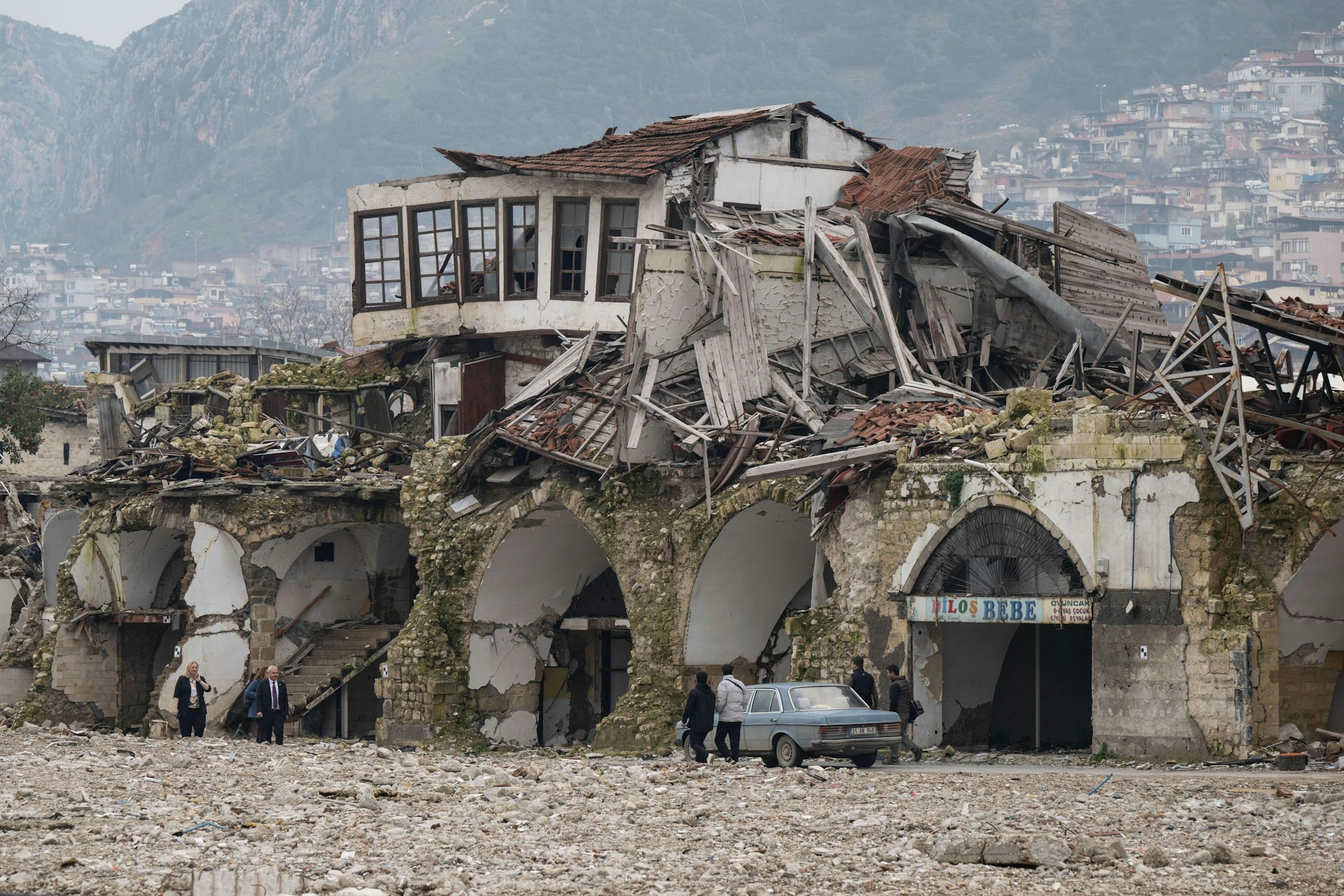 Menschen gehen in der Altstadt von Antakya an zerstörten Häusern entlang.