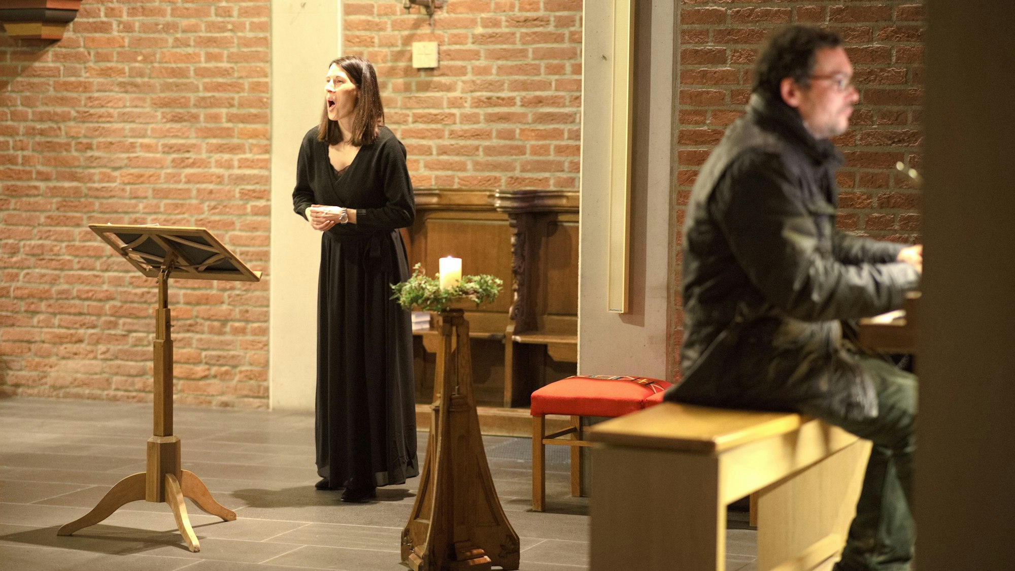 Die Sängerin Sonja Dehn, die an einem Pult steht, und der Organist Christophe Knabe während ihres Auftritts in der Großbüllesheimer Kirche.