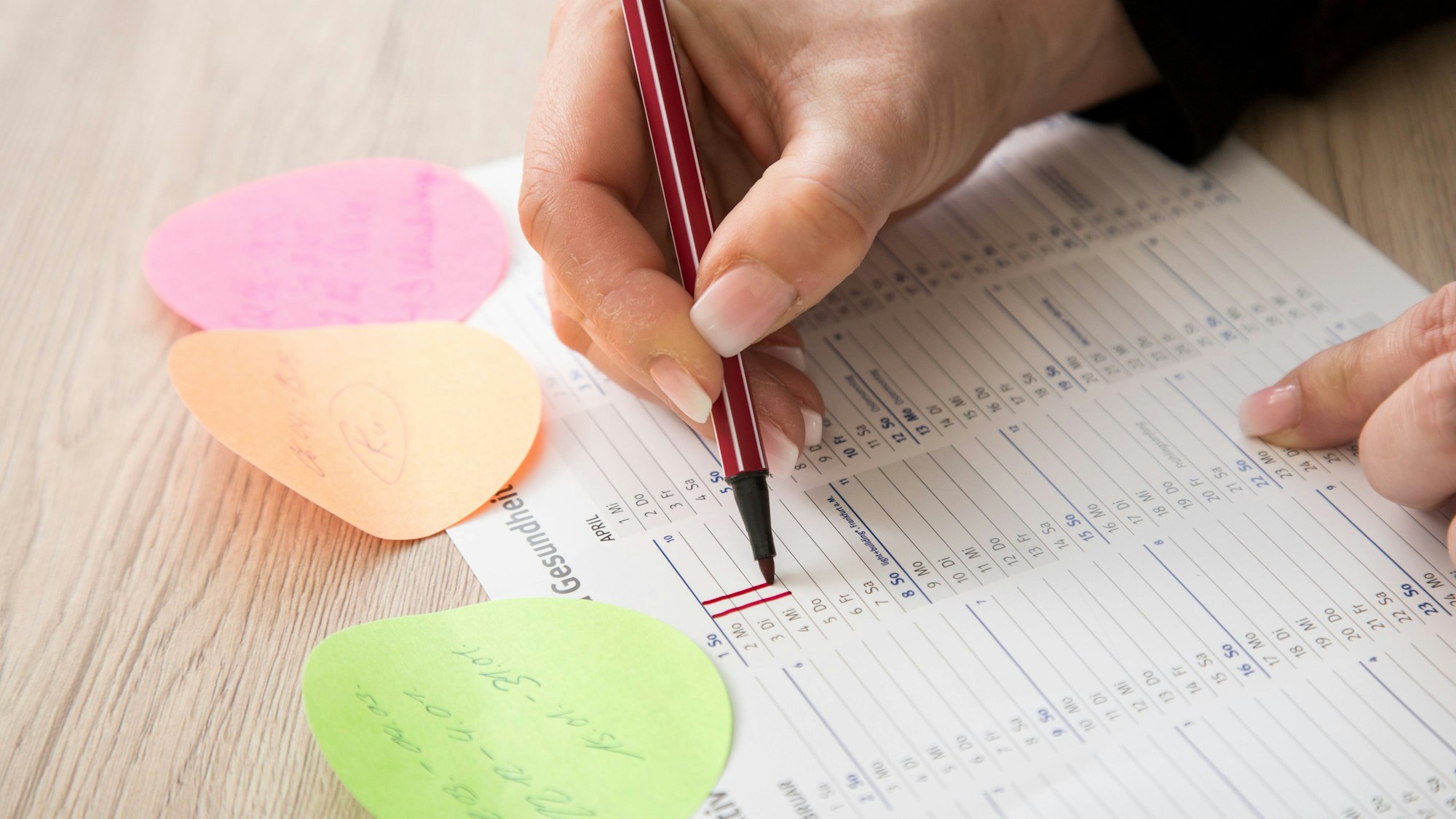 Eine Person markiert Tage in einem Kalender mit einem roten Stift.