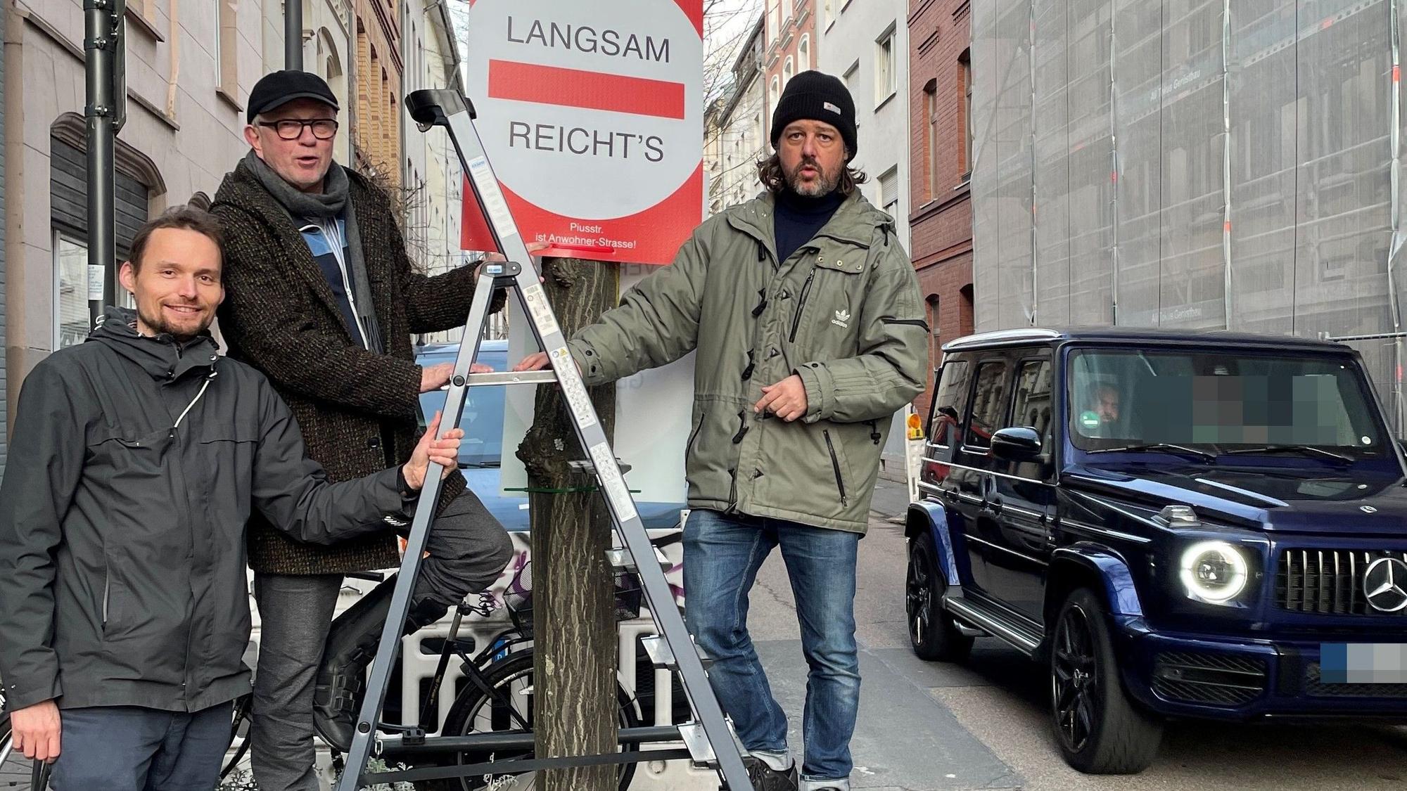 Drei Männer stehen um ein Baumbeet herum. Sie haben ein Schild aufgehängt.