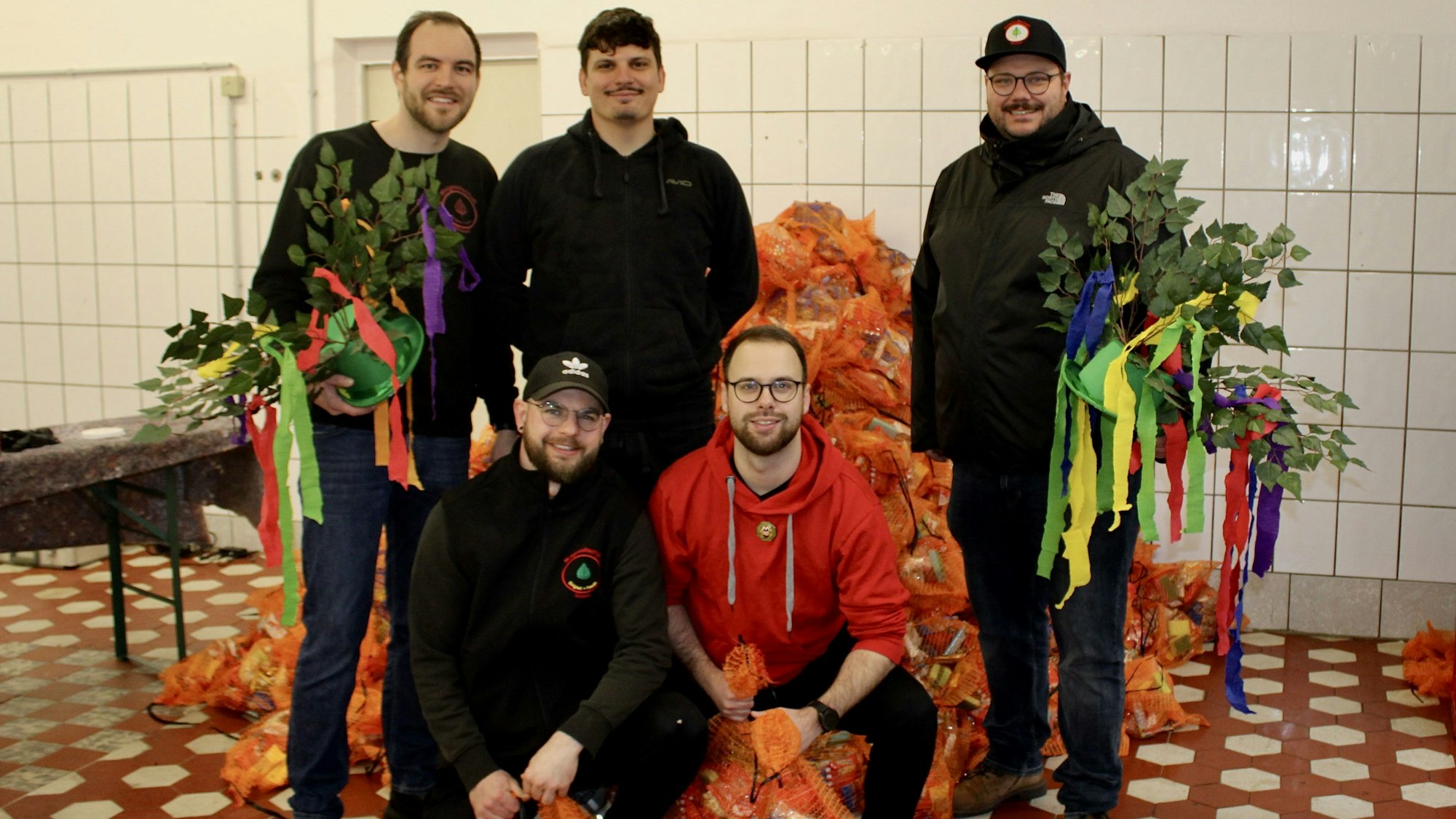 Vier Männer mit geschmückten Maiherzen und Kamellebeuteln.