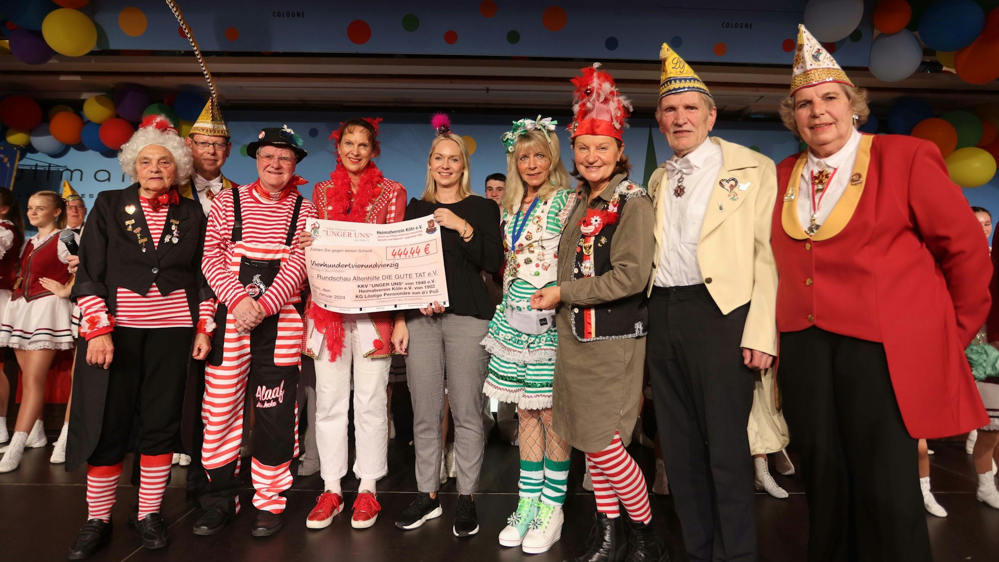 Julia Heinen nimmt einen Scheck der verkleideten Jecken entgegen.