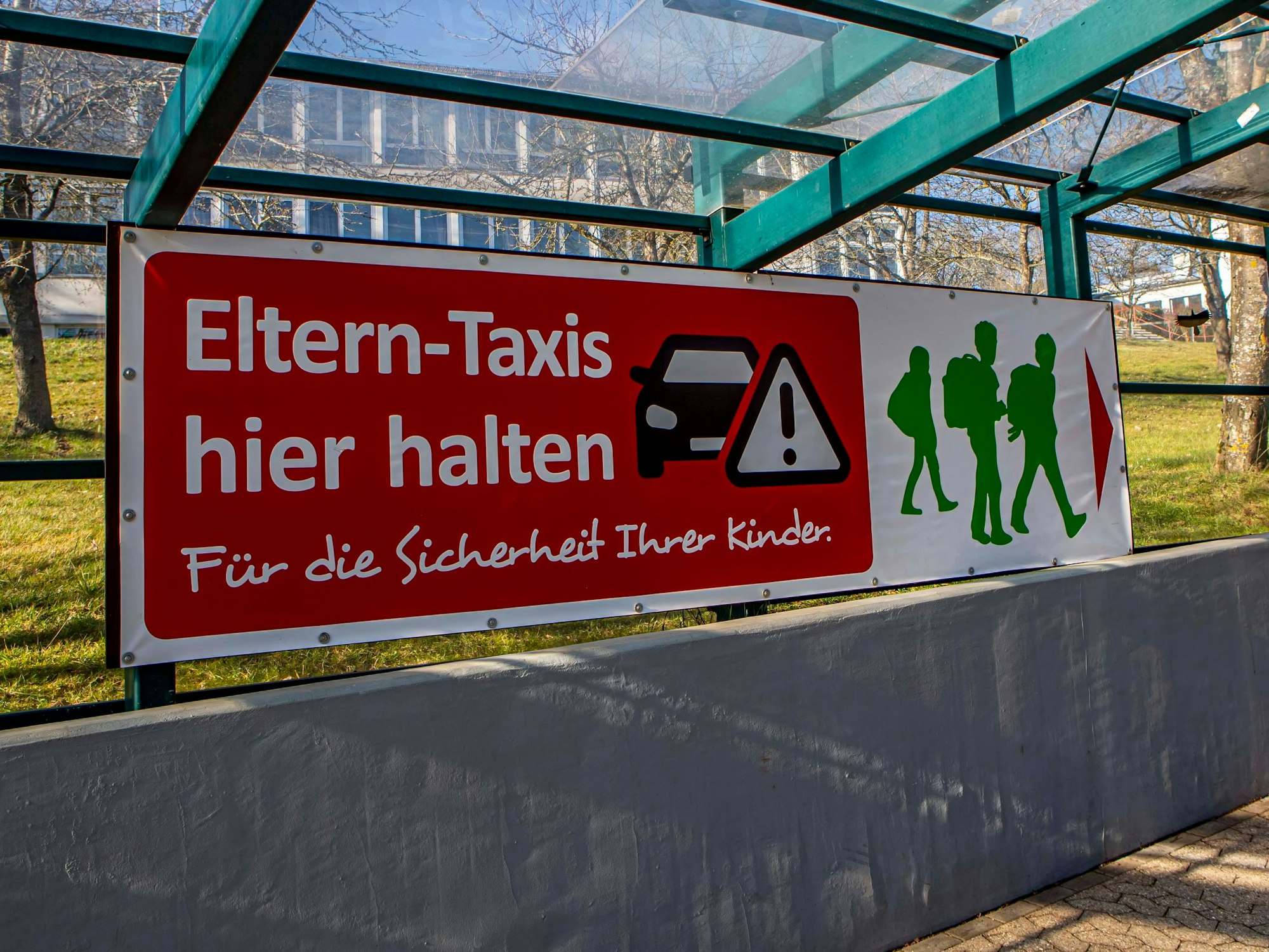 Ein Transparent mit der Aufschrift „Elterntaxis hier halten“.