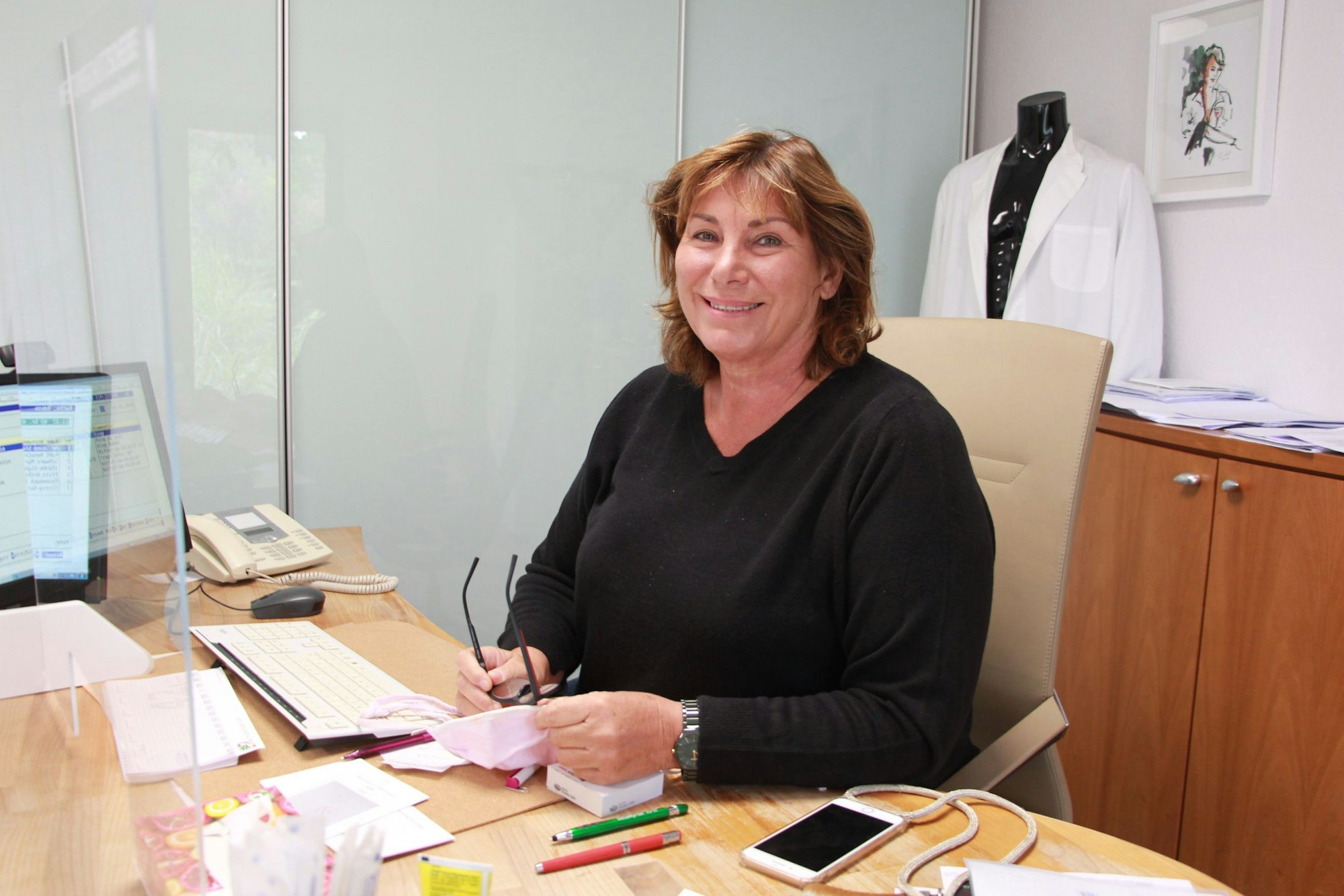 Eine Ärztin sitzt an ihrem Schreibtisch.