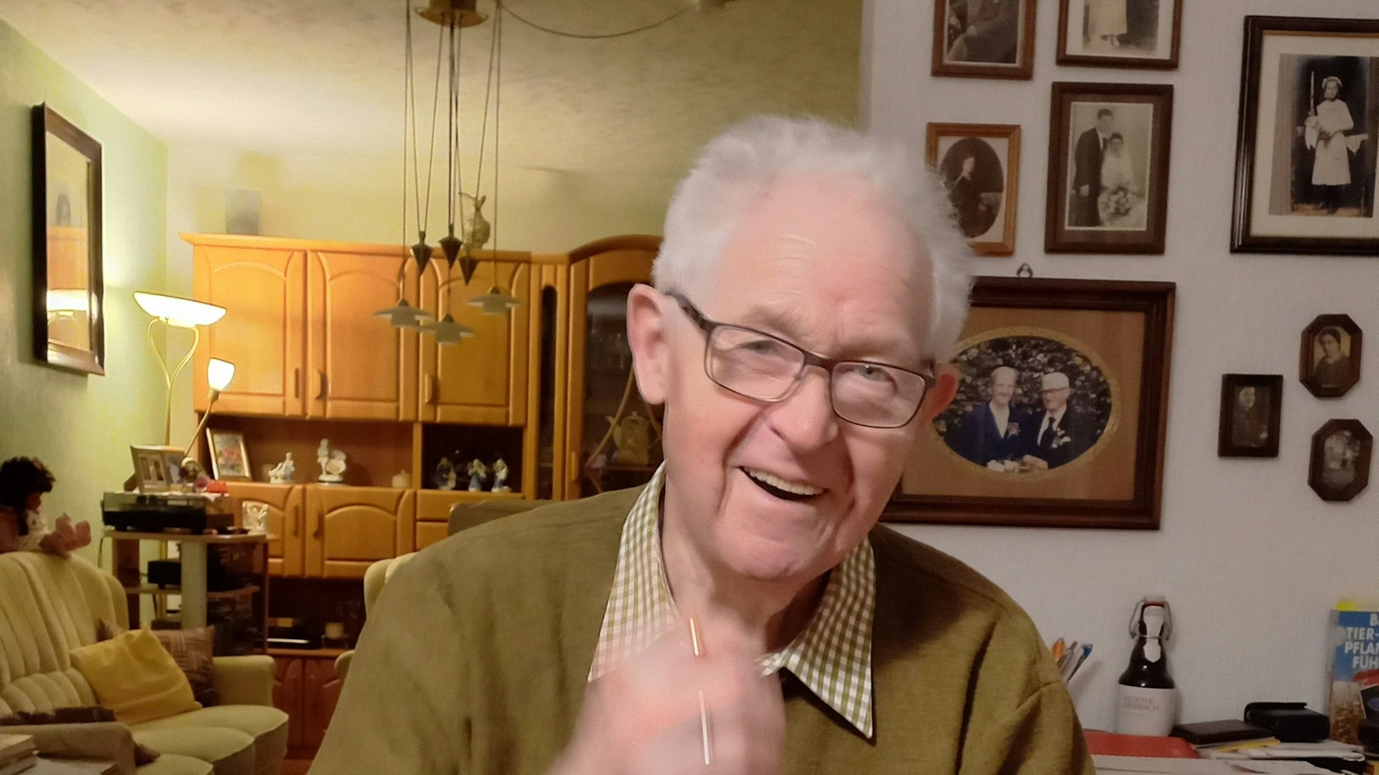 Ein älterer Herr sitzt in seinem Wohnzimmer.