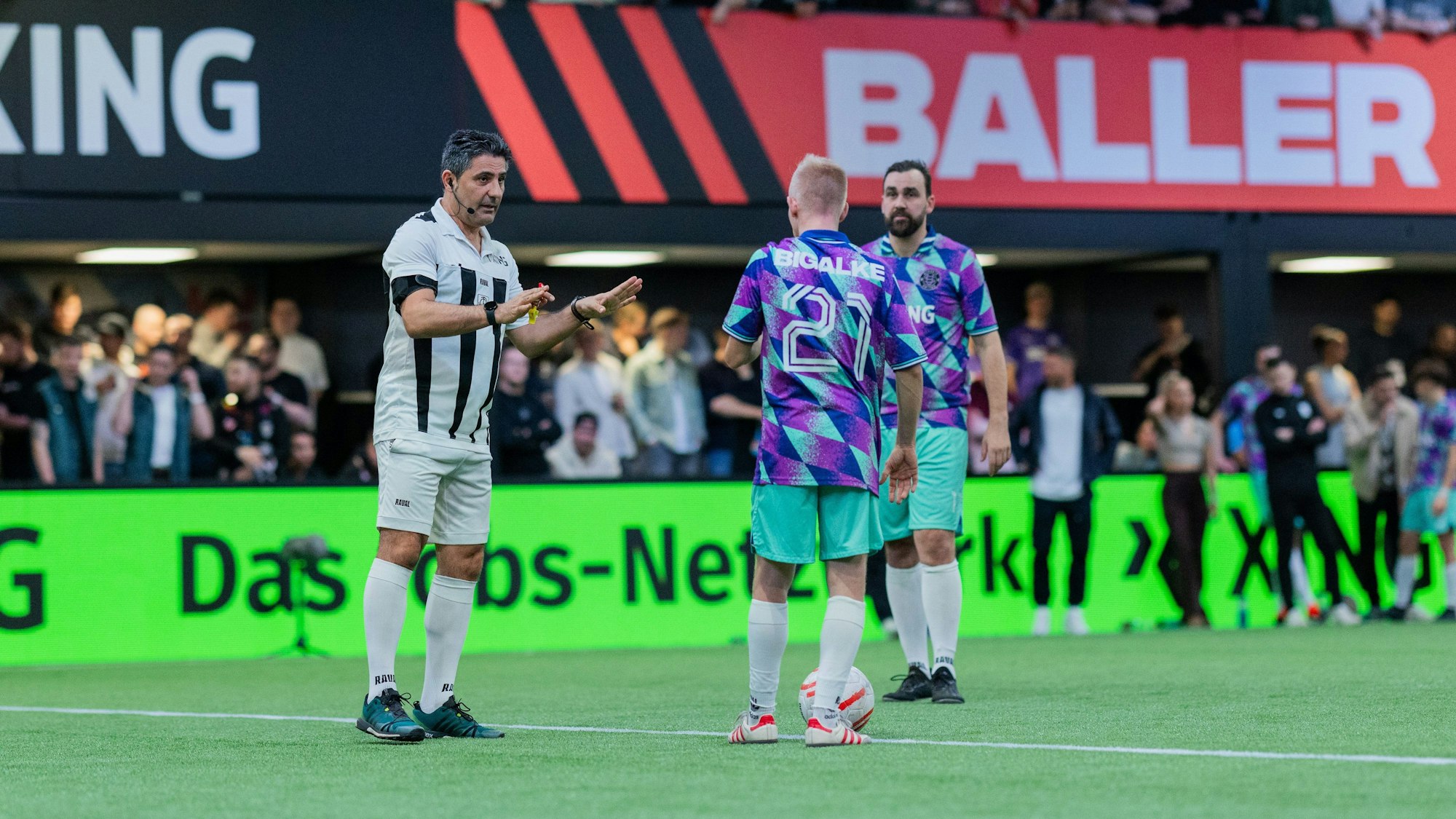 Babak Rafati, ehemaliger Bundesligaschiedsrichter, spricht auf dem Spielfeld in der Motorworld mit dem ehemaligen Bundesligaspieler Sascha Bigalke von Streets United.