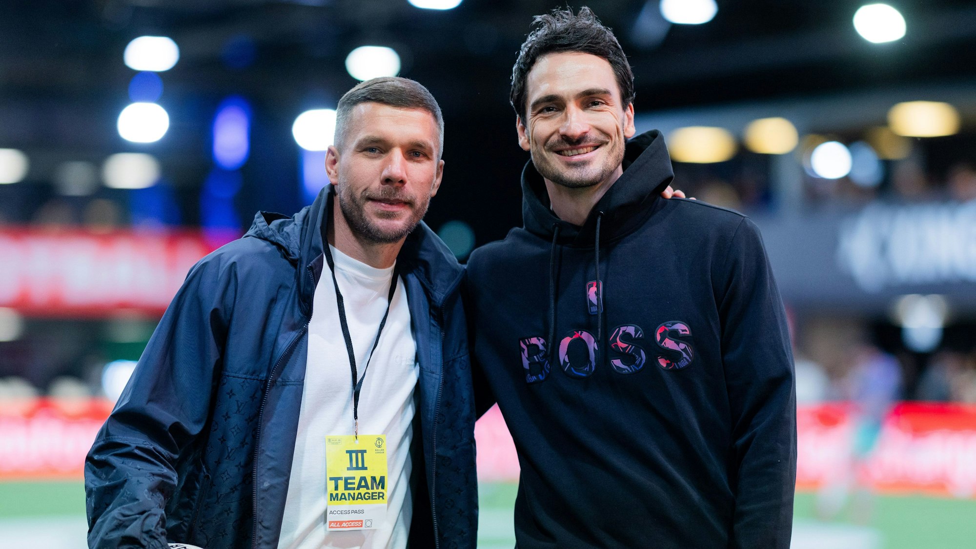 Mats Hummels von Borussia Dortmund, und Lukas Podolski, Präsidenten der Baller League, stehen auf dem Spielfeld in der Motorworld.