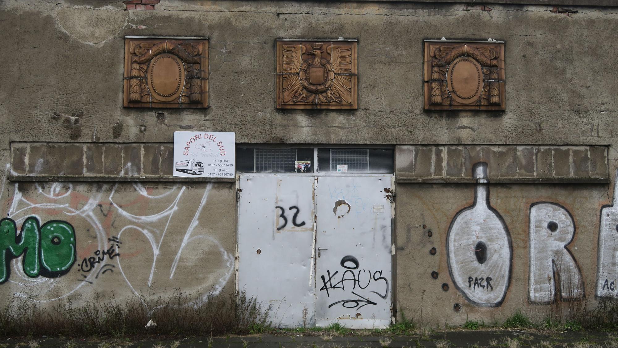 Blick auf Ornamente an einer mit Graffiti beschmierten Betonwand.