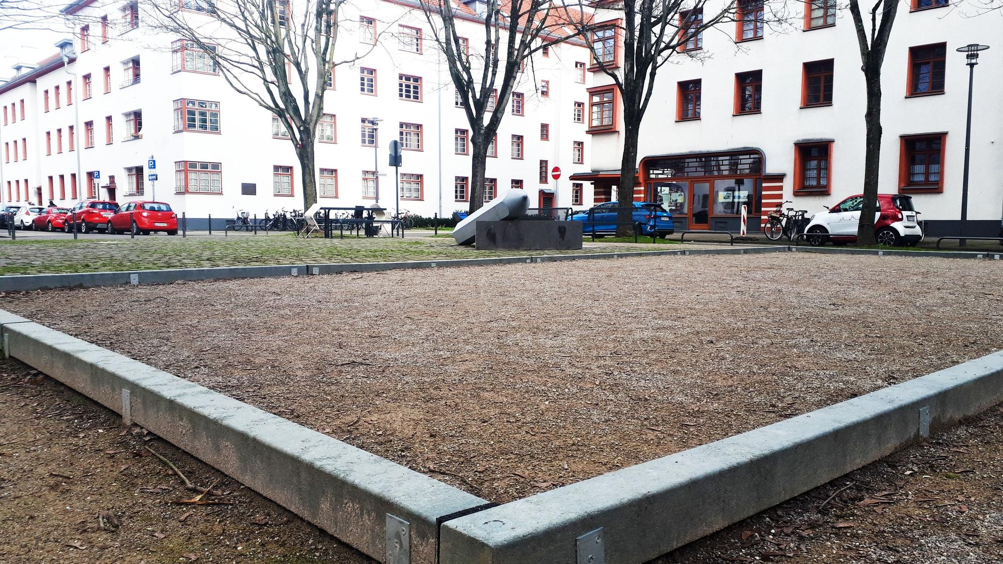 Blick auf einen Platz mit Bouleplatz vor einer Wohnsiedlung
