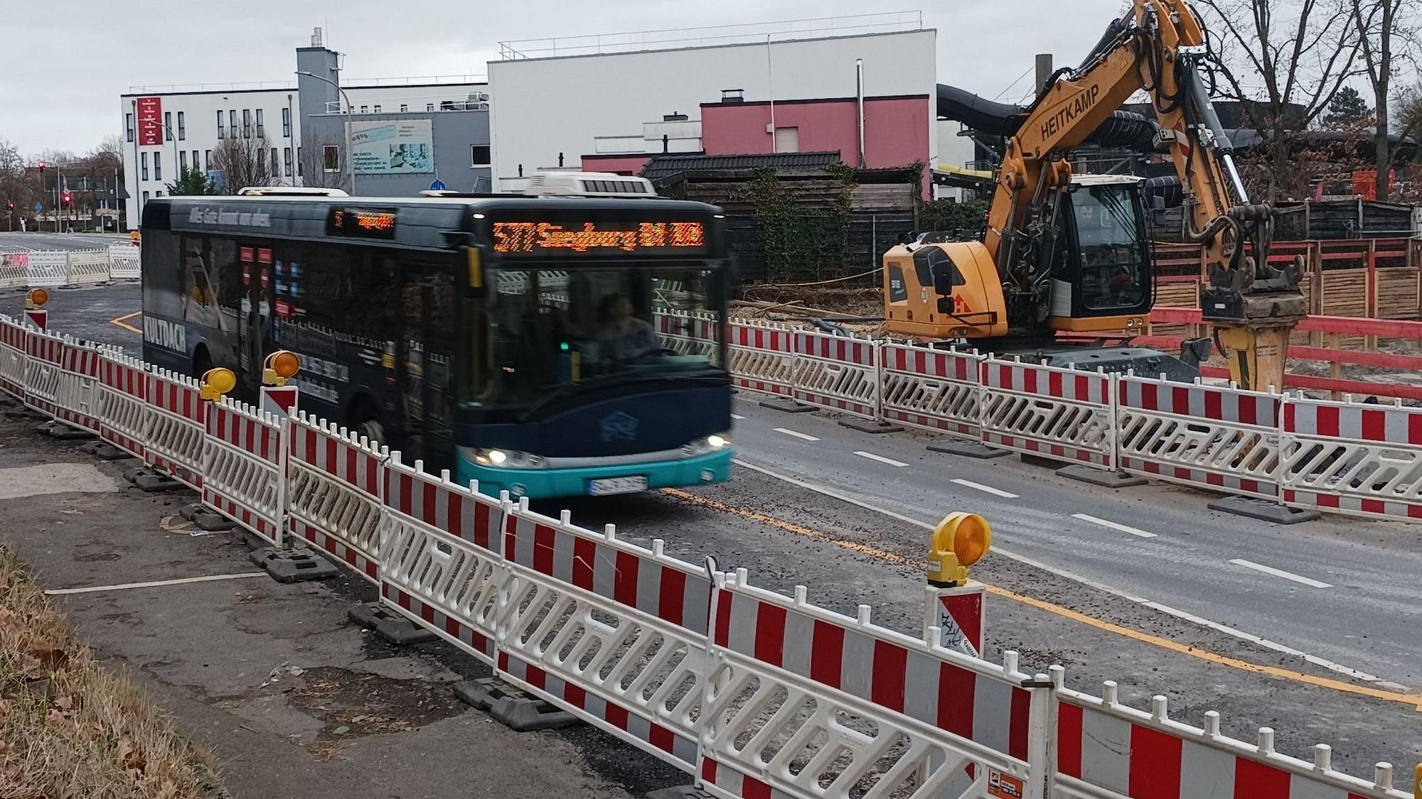 Ein Bus fährt durch eine Straßenbaustelle mit rotweißen Warnbaken