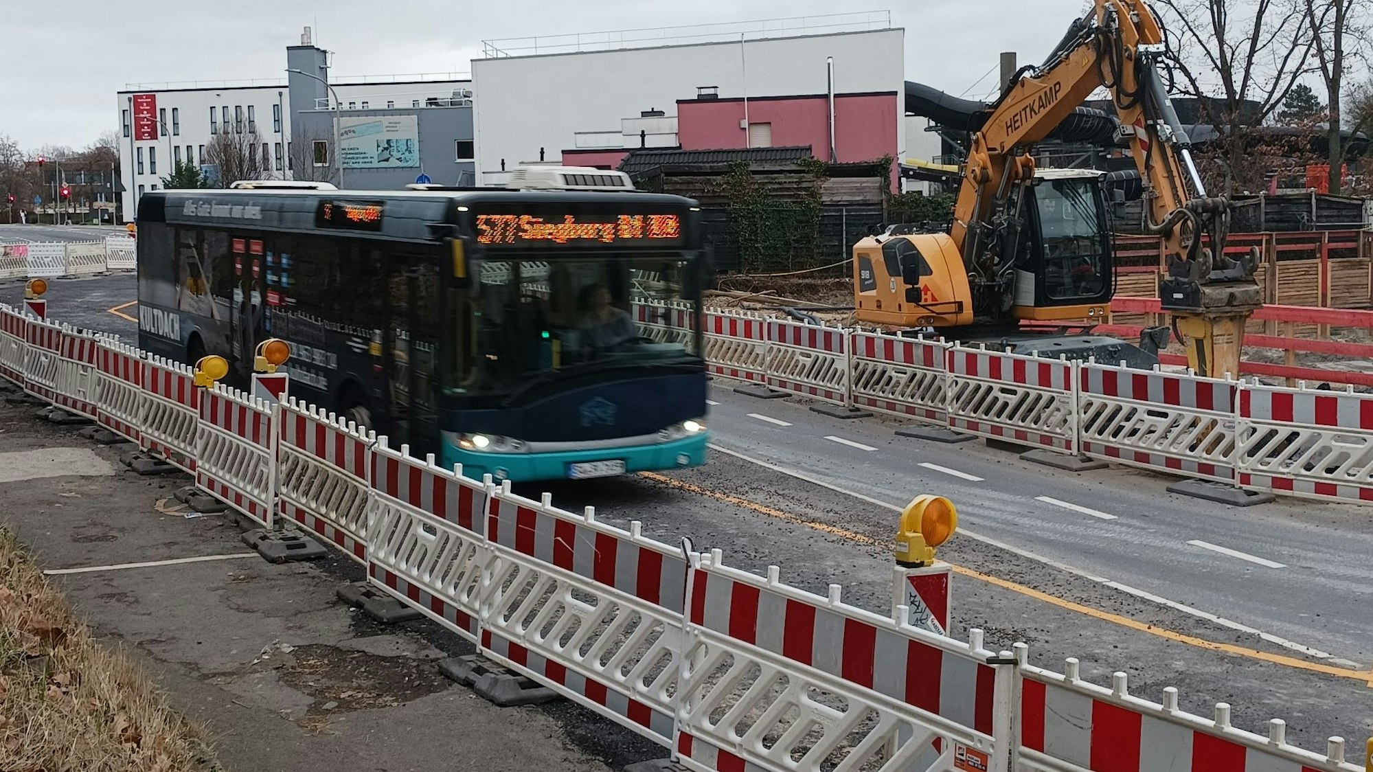 Ein Bus fährt durch eine Straßenbaustelle mit rotweißen Warnbaken