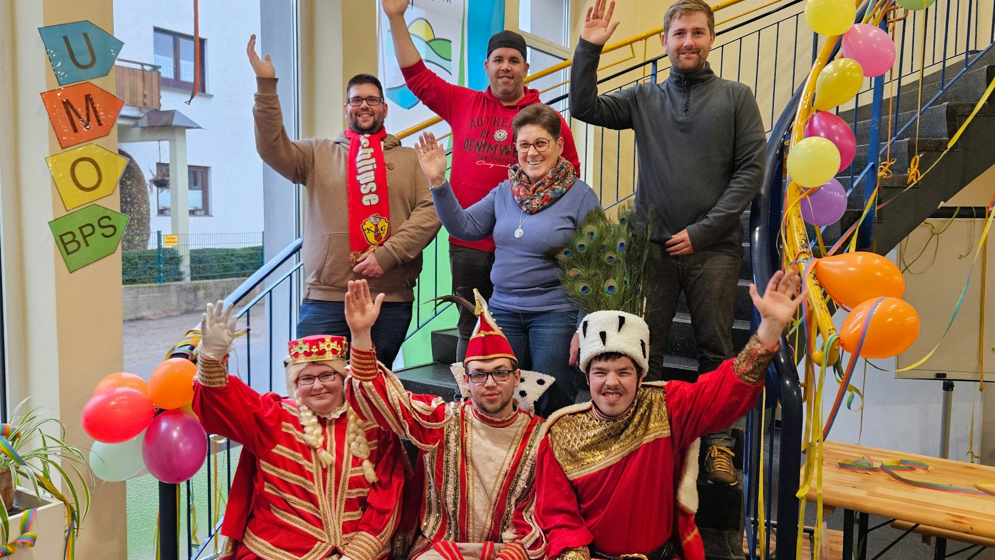 Das Dreigestirn der Sankt-Nikolaus-Schule, bestehend aus Jungfrau Ann-Kathrin Kesting, Prinz Maximilian Fünfzig und Bauer Yannick Herzet, sitzt auf einer Treppe. Dahinter stehen Tobias Geschwind, Erik Hensch, Doris Hensch und Thomas Müller.