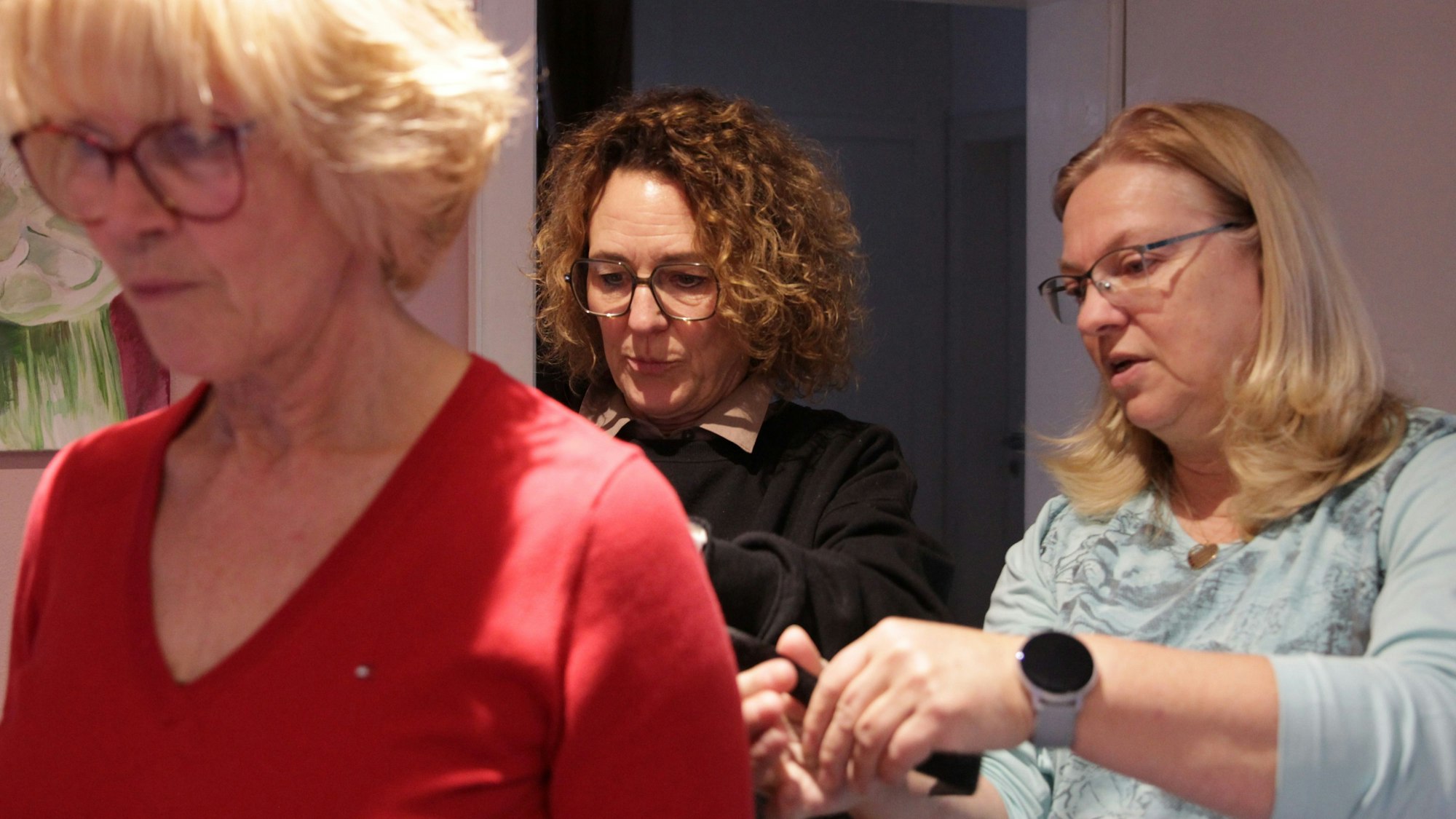 Zwei Frauen testen verschiedenen Befestigungsmöglichkeiten am Rücken einer dritten Frau.