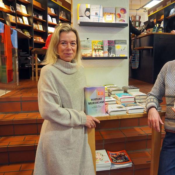 Zwei Frauen stehen in einer Buchhandlung. Jede hat ein Buch in der Hand.