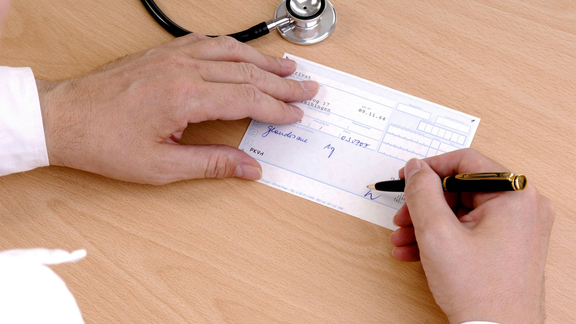 Ein Mann füllt ein auf dem Tisch liegendes Rezept aus, daneben liegt ein Stethoskop