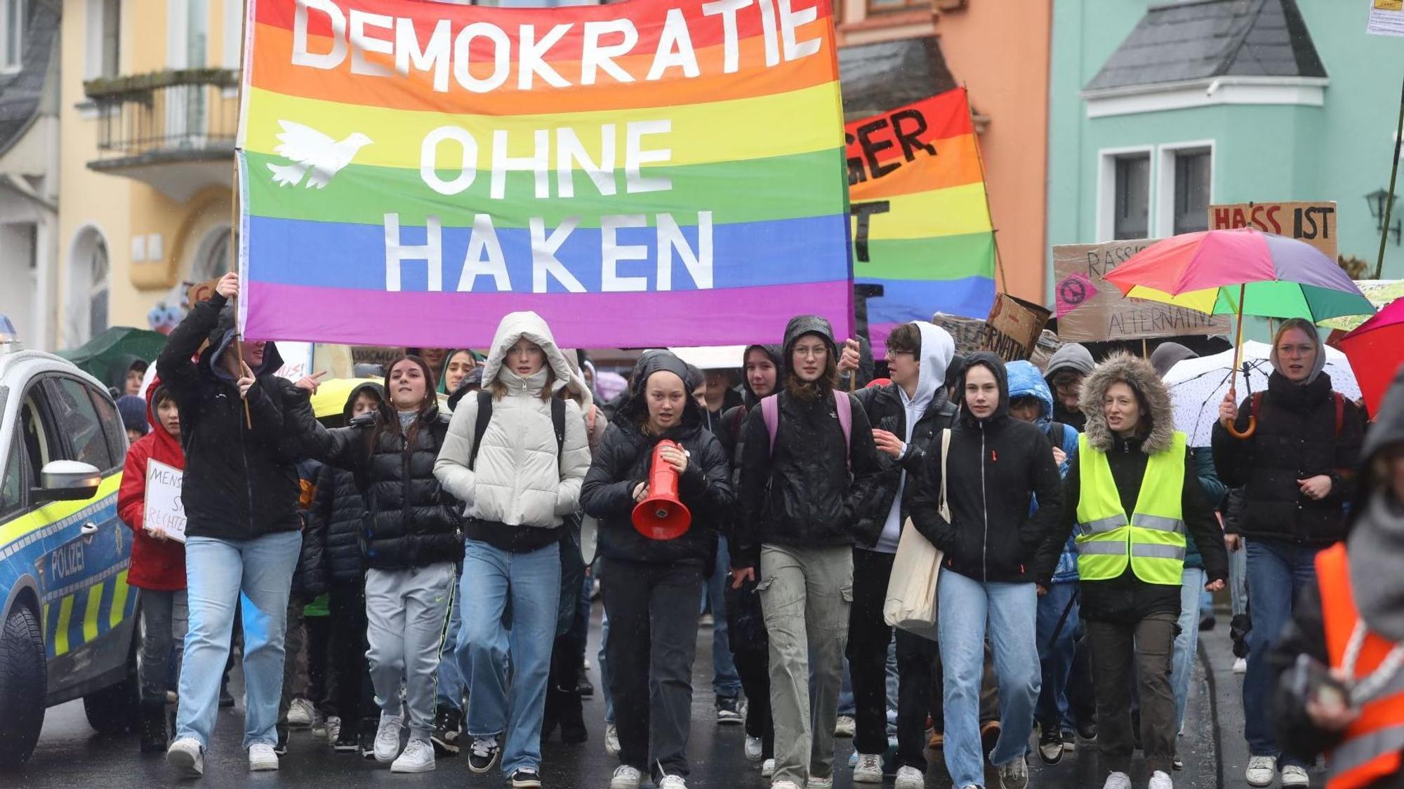Schüler ziehen durch eine Straße. Auf einem bunten Transparent steht das Motto der Demonstration: „Demokratie ohne Haken“