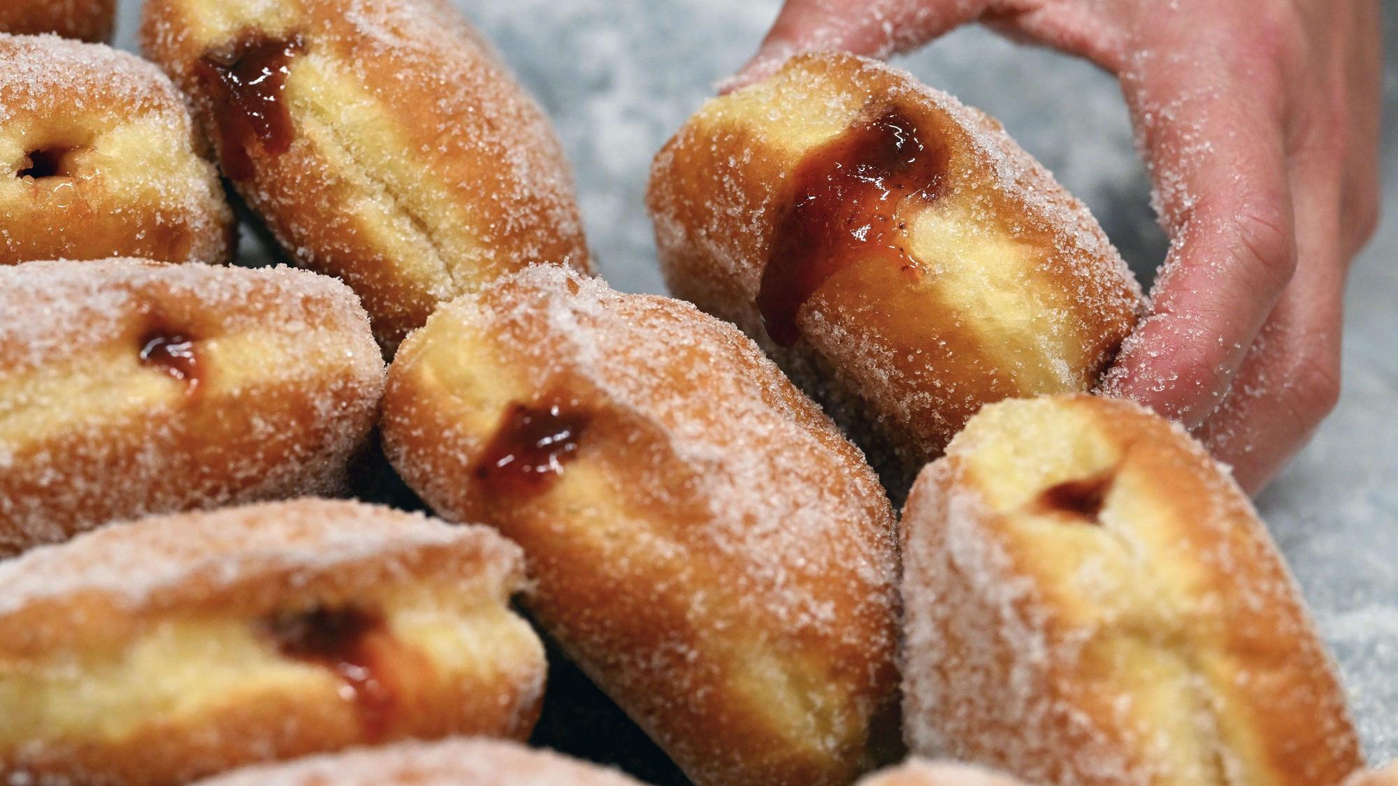 Frisch gebackene und mit selbstgemachtem Pflaumenmus gefüllte Pfannkuchen liegen auf einem Backblech in der Berliner Sugarclan Gmbh.