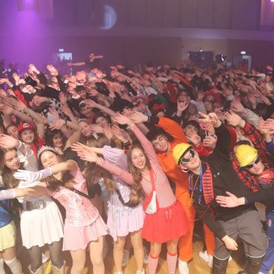 Verkleidete Jugendliche werfen die Arme in die Luft.