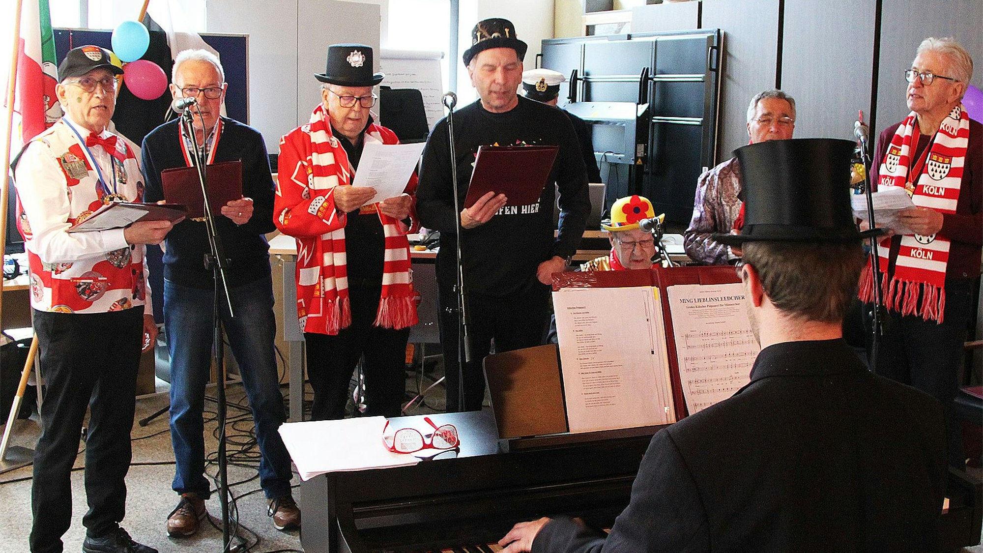 Die Eifelperlen singen Kölsche Lieder. Ein Mann mit Zylinder ist von hinten am Piano zu erkennen.