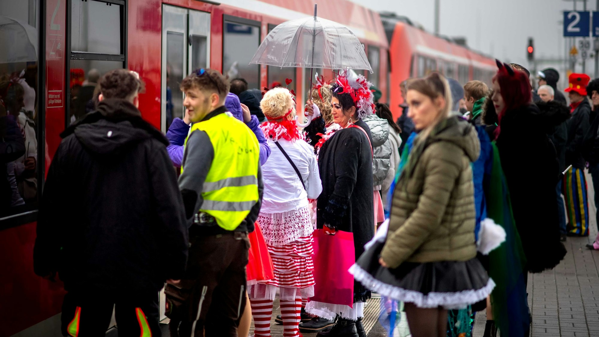 Kostümierte Karnevalsfans warten am Euskirchener Bahnhof auf den Zug nach Köln.