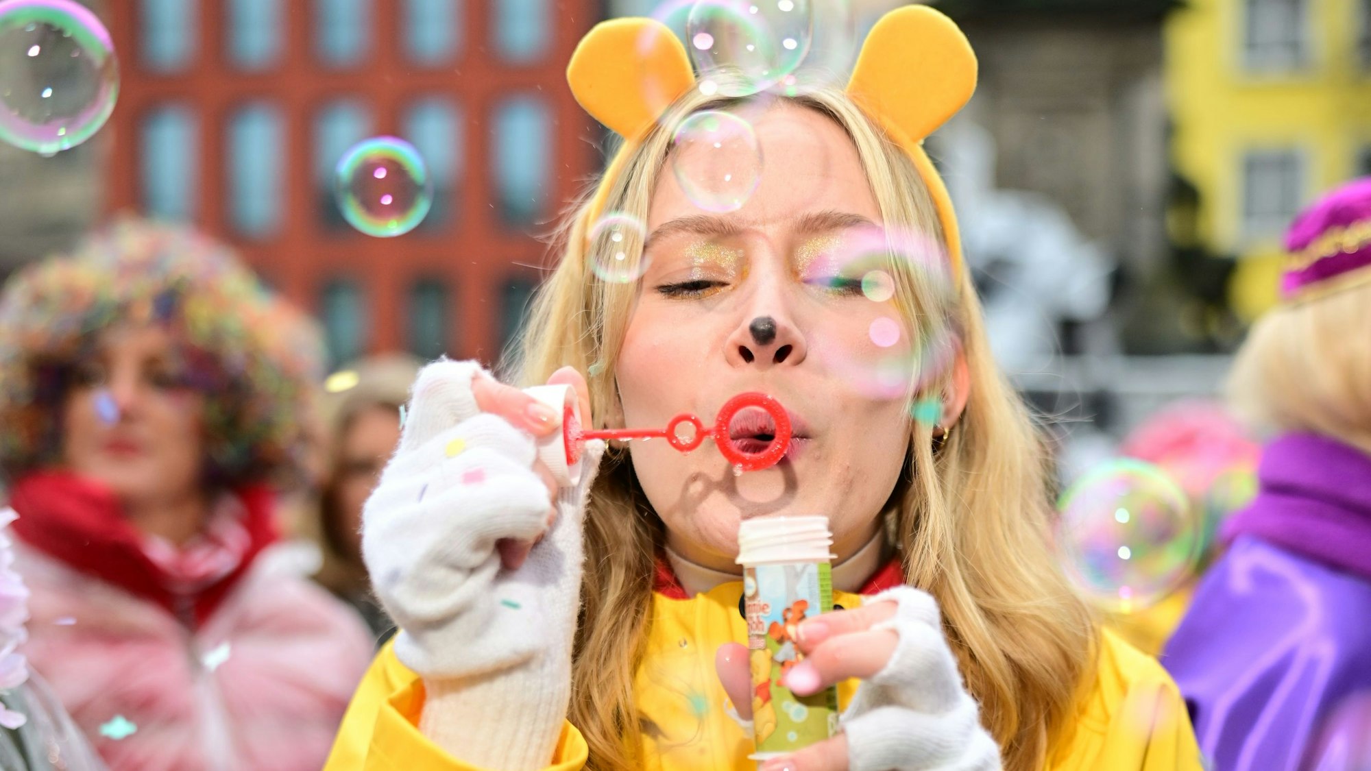 Eine Frau im Regenmantel pustet Seifenblasen.