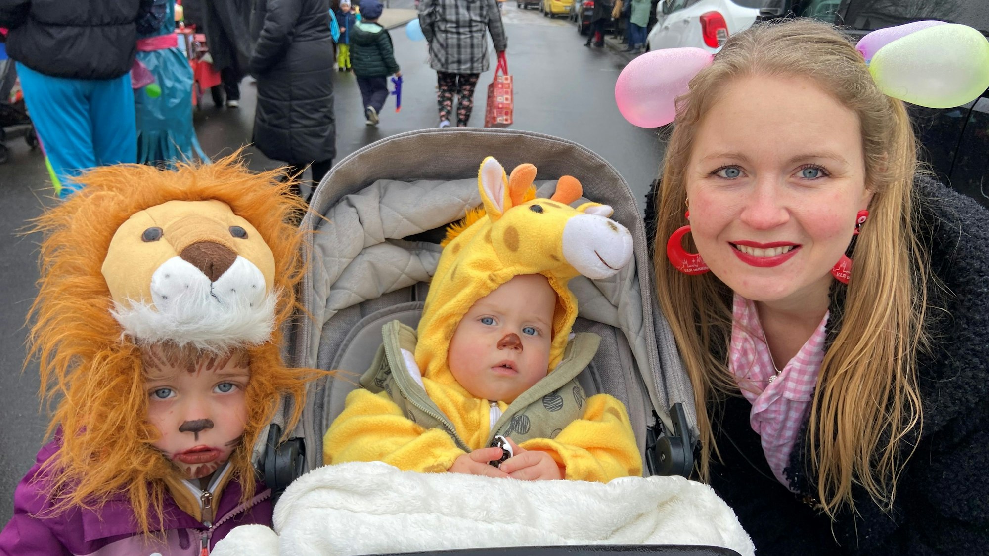 Auf dem Bild ist eine Mutter mit ihren kostümierten Kindern zu sehen