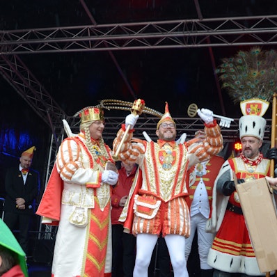 Da ist das Ding! Prinz Tobi I., flankiert von Jungfrau Martina und Bauer Sascha, präsentiert den Stadtschlüssel, den er in die Höhe reckt. Am Bildrand steht der geschlagene Bürgermeister Sacha Reichelt.