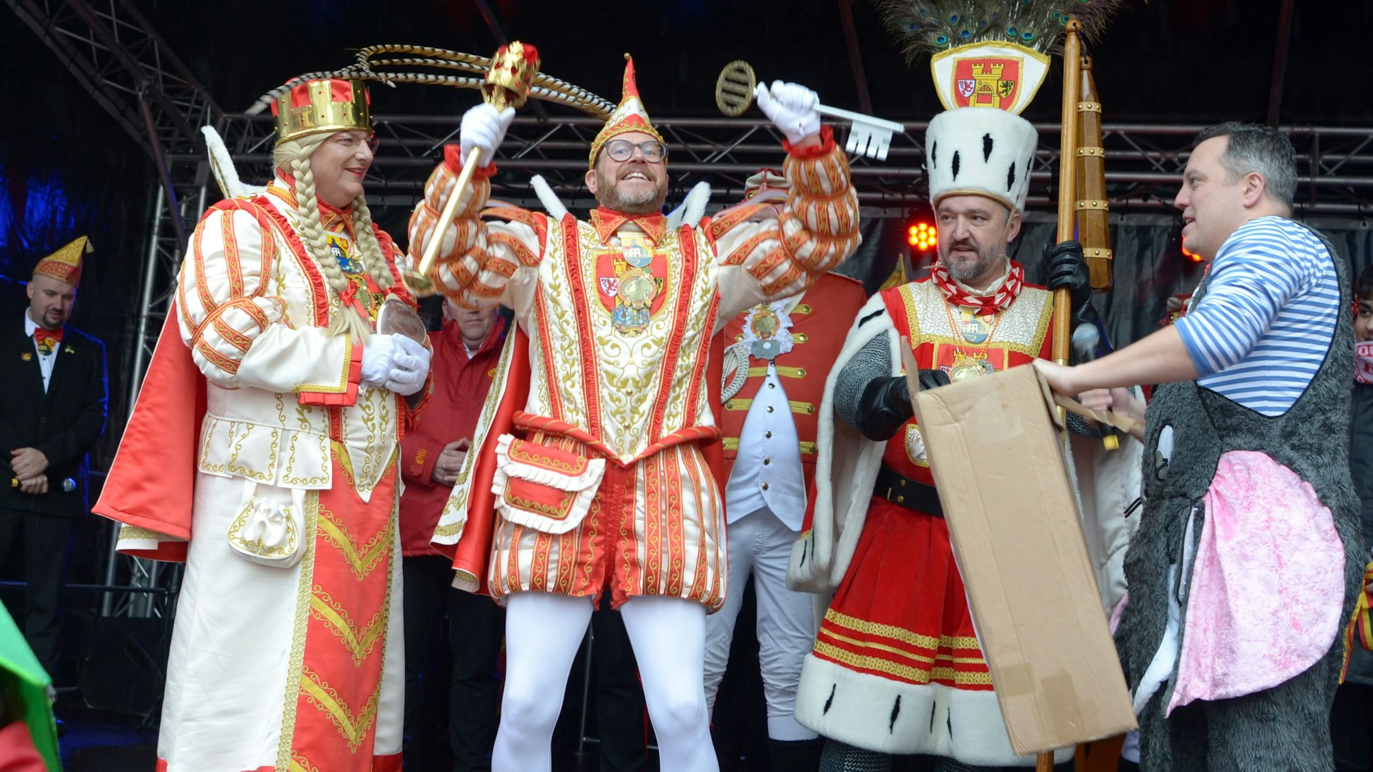 Da ist das Ding! Prinz Tobi I., flankiert von Jungfrau Martina und Bauer Sascha, präsentiert den Stadtschlüssel, den er in die Höhe reckt. Am Bildrand steht der geschlagene Bürgermeister Sacha Reichelt.