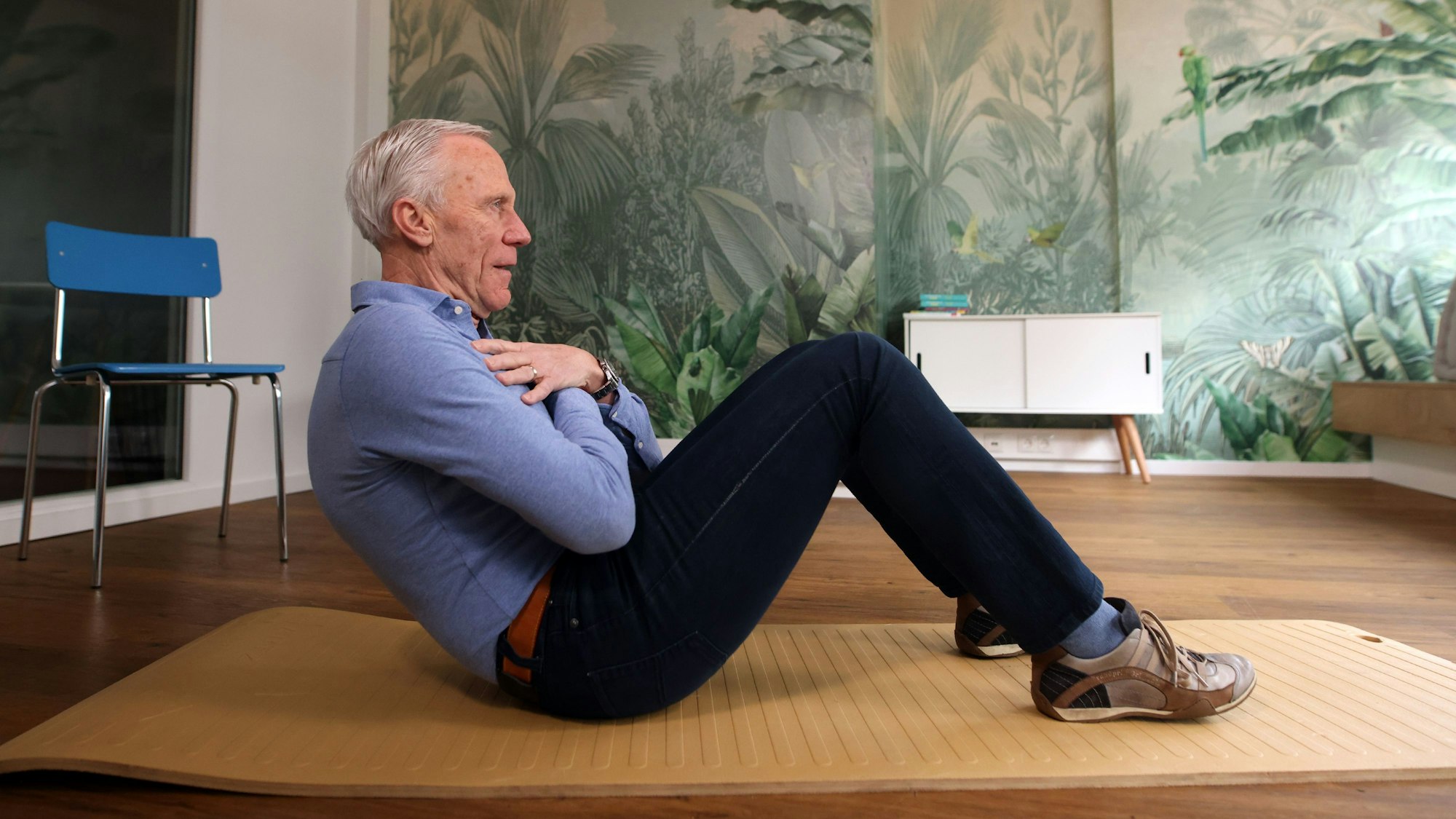 Noch eine Halteübung: Auf den Boden setzen, Knie beugen, Füße aufsetzen, Arme verschränken und ein Stück mit dem Rücken nach hinten sinken. Und dann: Halten, halten, halten.