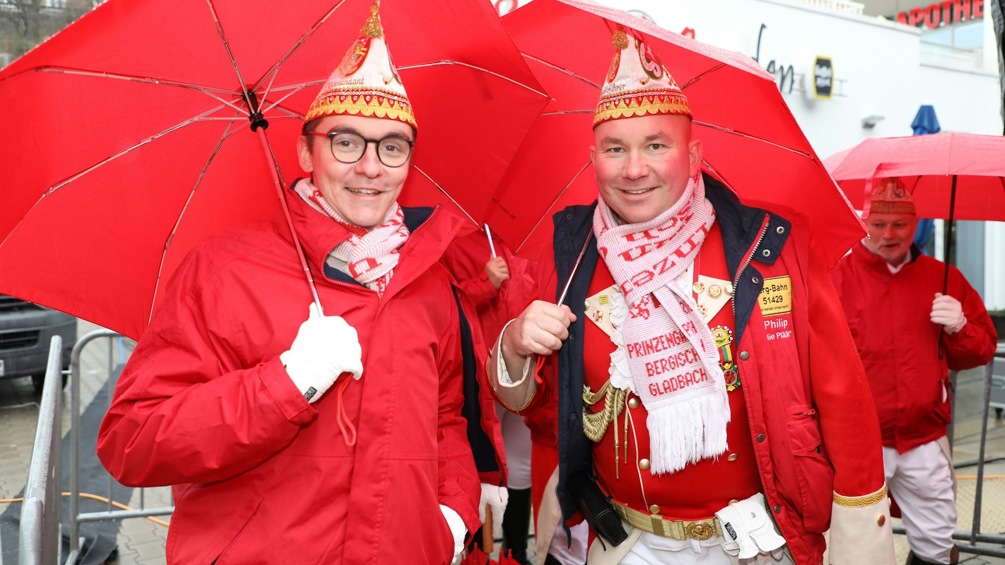 Zwei Prinzengardeisten stehen unter roten Schirmen beim Rathaussturm in Bensberg.