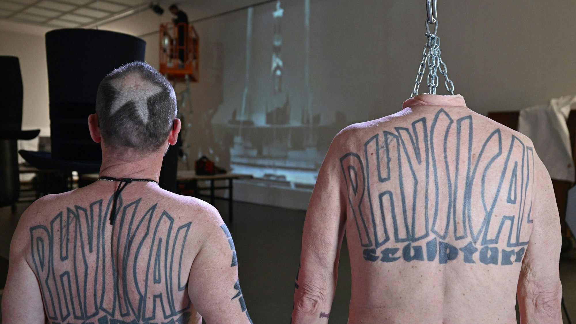 Der Künstler Flatz (l) steht neben einer naturgetreuen Nachbildung seiner Haut und seines Körpers an einem Fleischerhaken hängend.