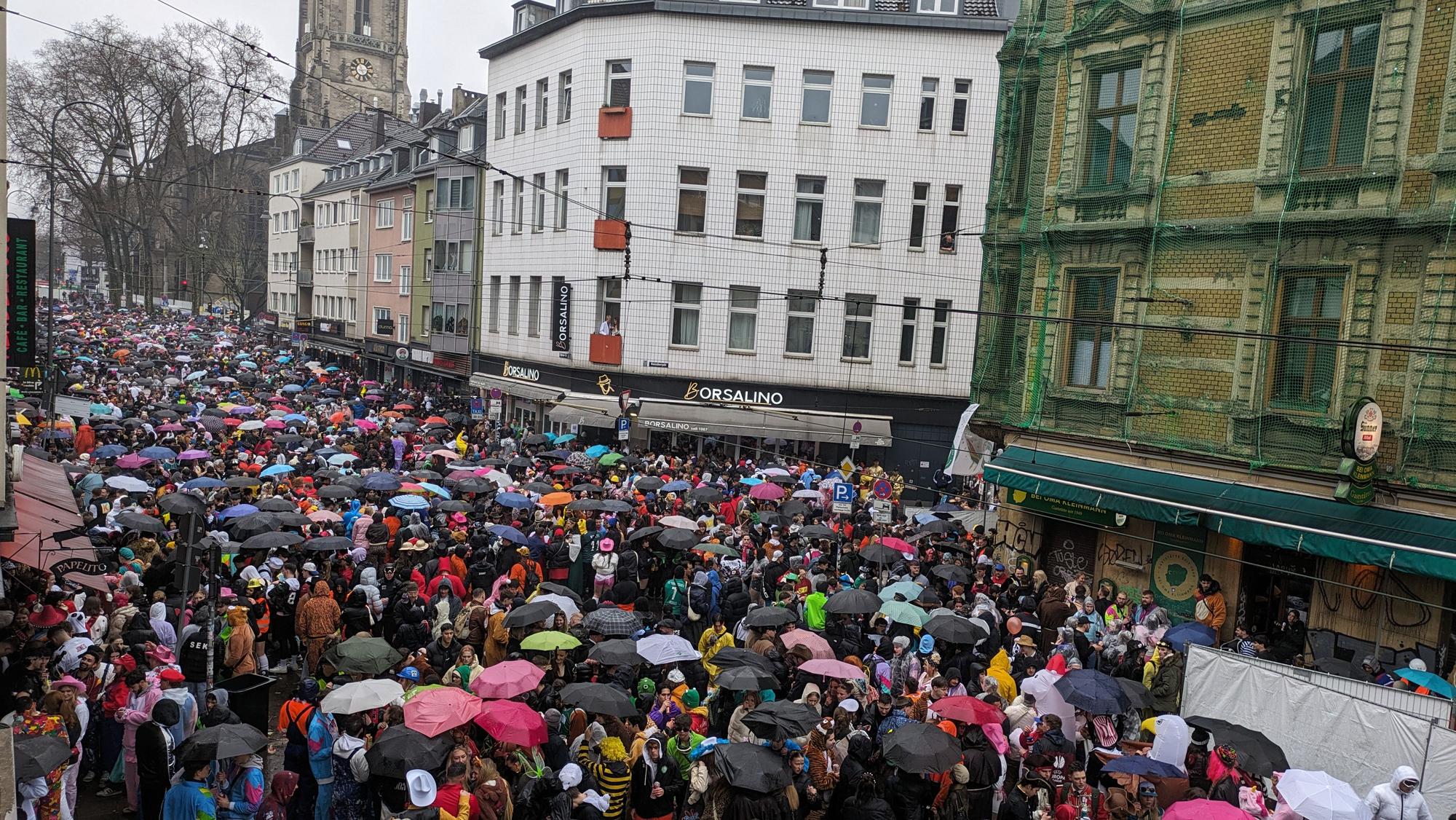 Weiberfastnacht 2024: Die Zülpicher Straße ist gut besucht, Regenschirme sind das Accessoire des Tages