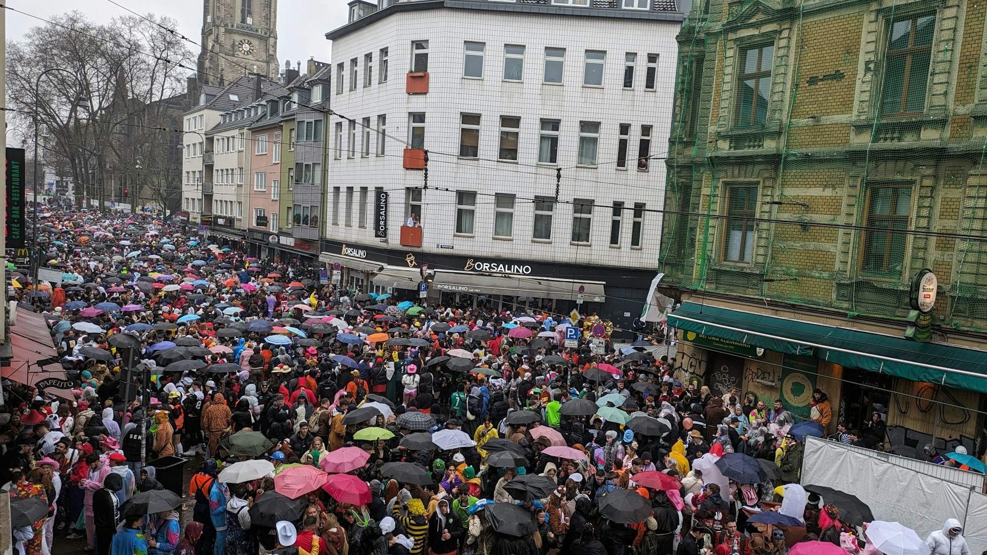 Weiberfastnacht 2024: Die Zülpicher Straße ist gut besucht, Regenschirme sind das Accessoire des Tages